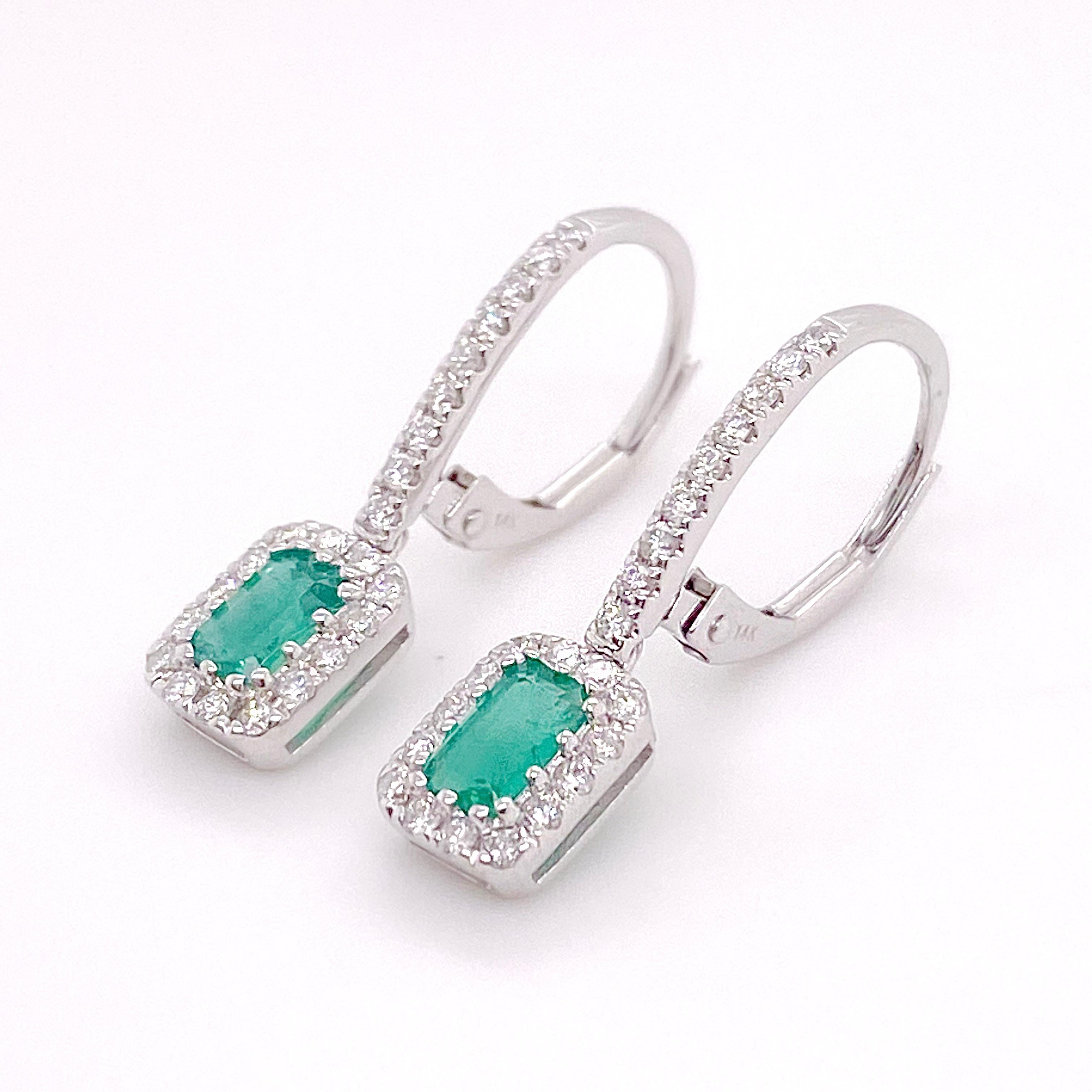 These gorgeous 14 karat white gold emerald and diamond drop earrings are perfect for a dressier occasion or for a wedding! The emerald cut green emerald is set beautifully in the center of 24 diamonds and the tops of the earrings have a strong