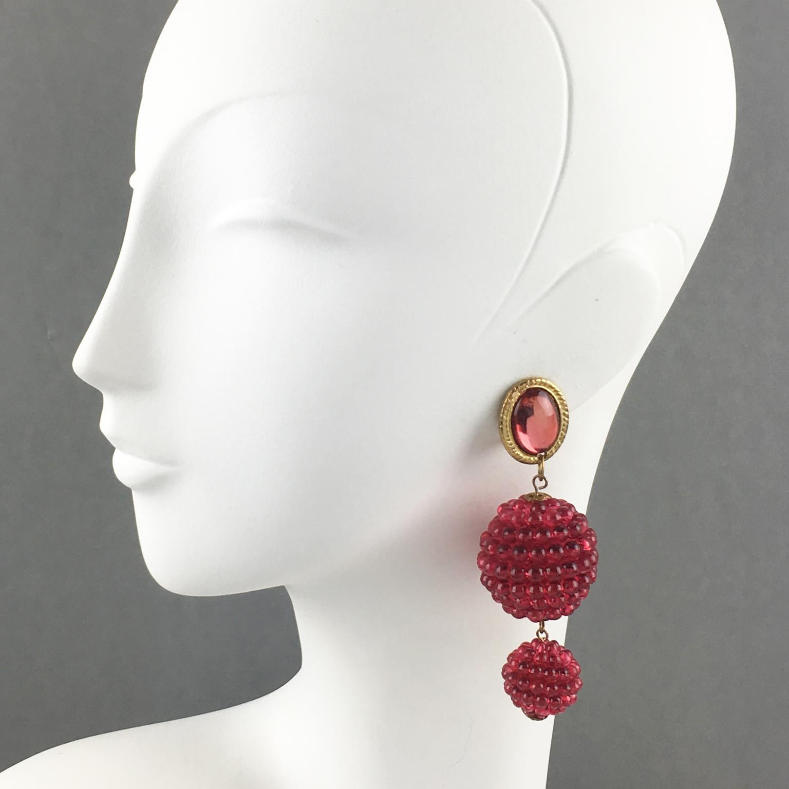 These lovely dangling clip-on earrings have a playful design with textured raspberry-shaped Lucite beads in a transparent fuchsia-pink color. The long dangling shape boasts gilt metal hardware fastenings topped with a light pink-red mirror effect