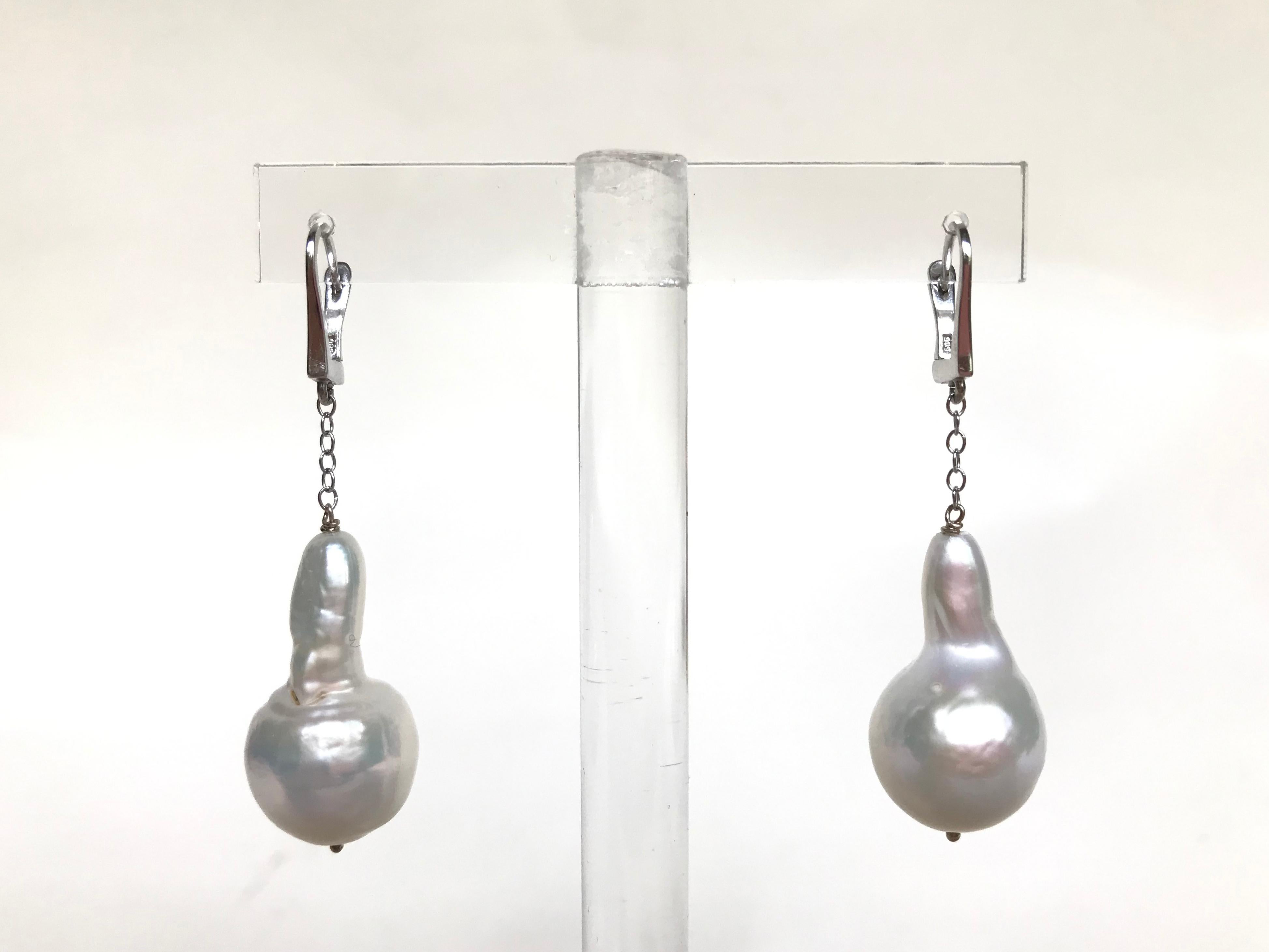 These dangle white baroque pearl earrings with 14k white gold chain and lever-back are stunning. The large white pearl hangs from the 14k white gold chain, giving these dangle earrings drama as they sway with movement. The 14k white gold lever-back