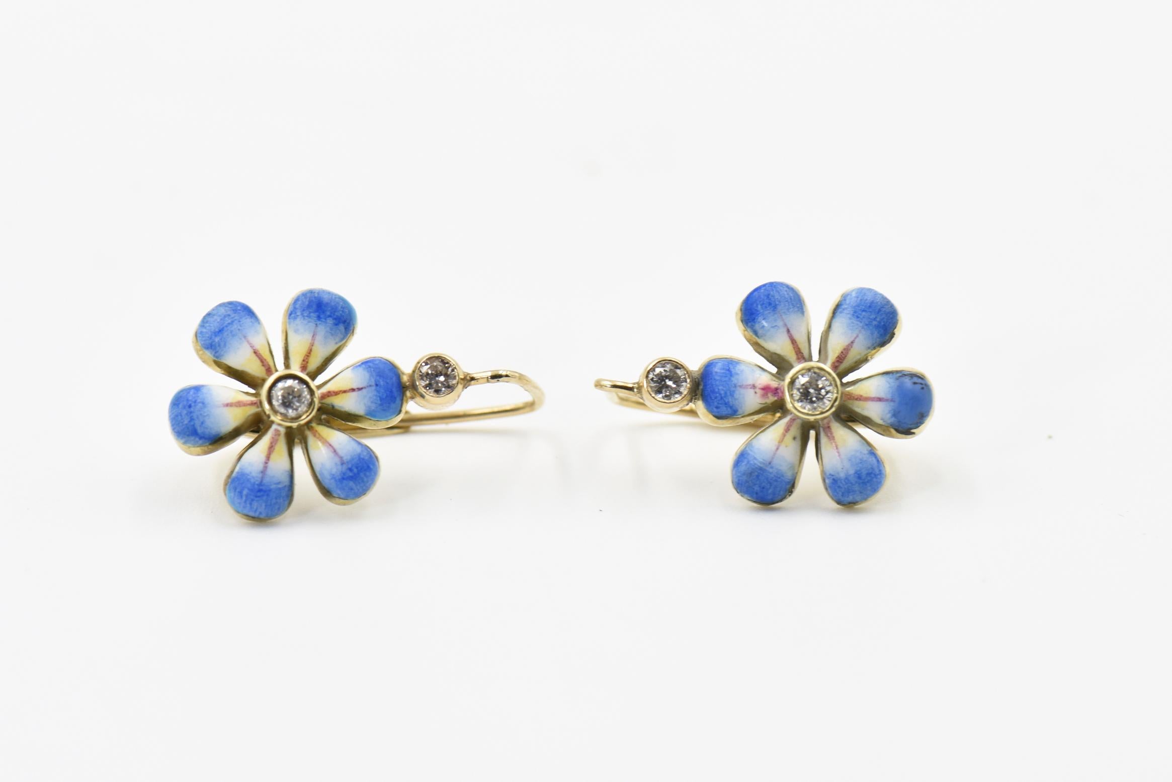 This pair of blue enamel daisy earrings are part of the daisy line, a beautiful handmade line of jewelry by Sandra J. Sensations. At the top of the earrings is a small diamond that is attached to a blue enamel dangling flower.  Each flower is hand