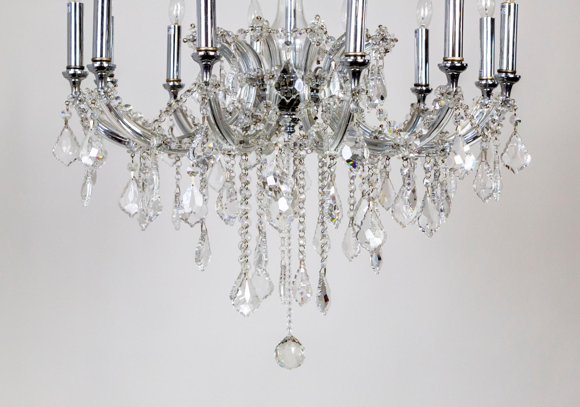A Bohemian glass chandelier with 12 arms with garlands of finely cut crystals and lengthy, dangling, beaded strands finished with large pendeloque crystals and a faceted ball; chrome colored candle covers and hardware, with gold floral painted