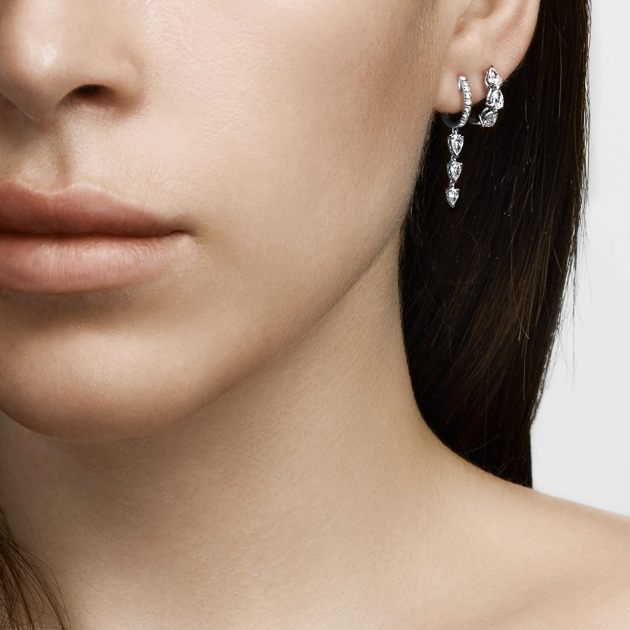 These delicate huggie hoops will be the most versatile earring in your wardrobe. Crafted in 18-karat white gold, the hoops are set with round diamond pavé. Three pear-shaped diamonds hang from each hoop, providing subtle movement and shine. Wear