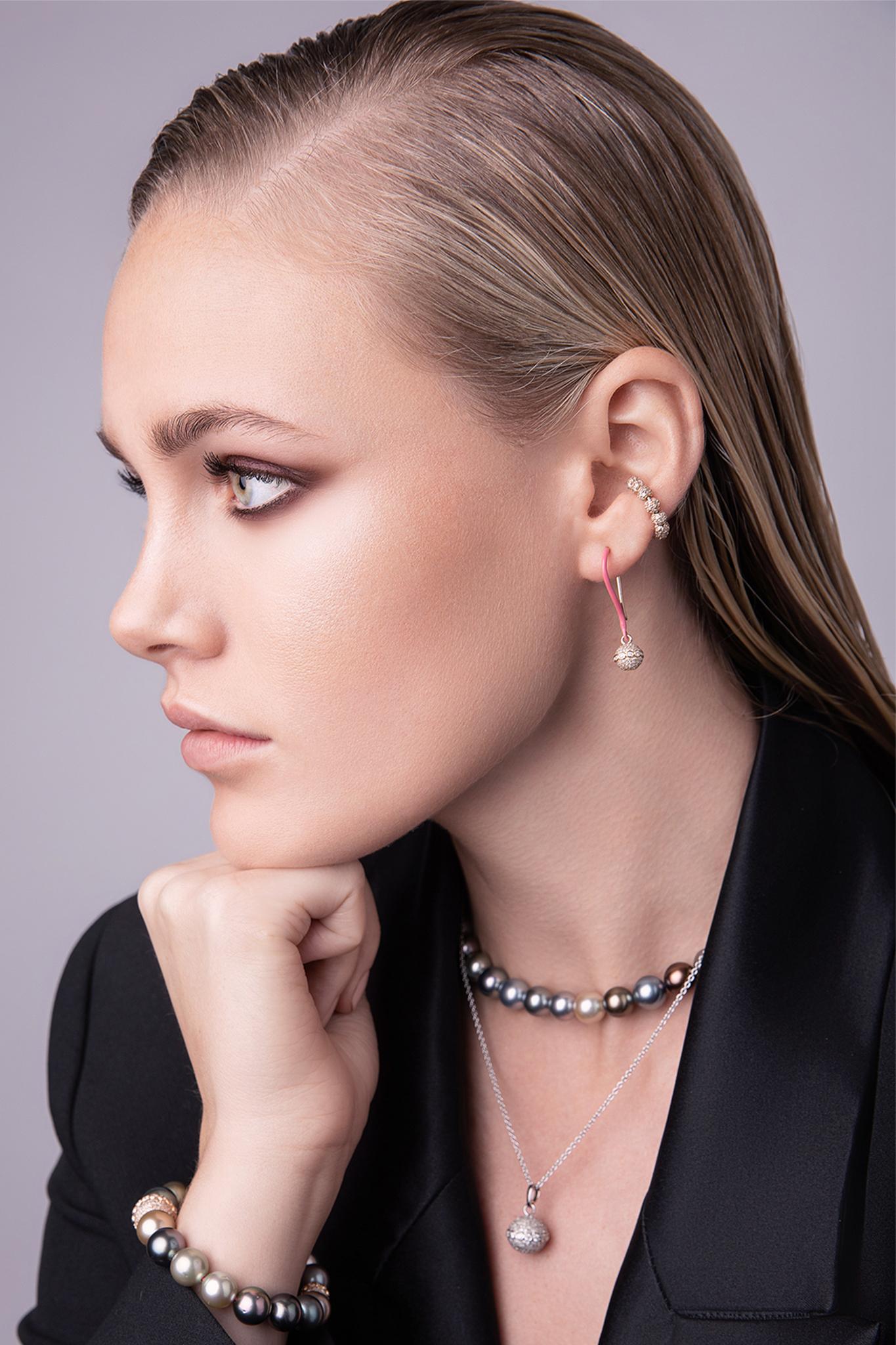 These hangers are a sculptural arrangement, carefully playing with the shape of a diamond sphere. These 18-karat yellow gold dangling diamond encrusted orb earrings are hand-painted in a beautiful jet black enamel. A striking effect due to its
