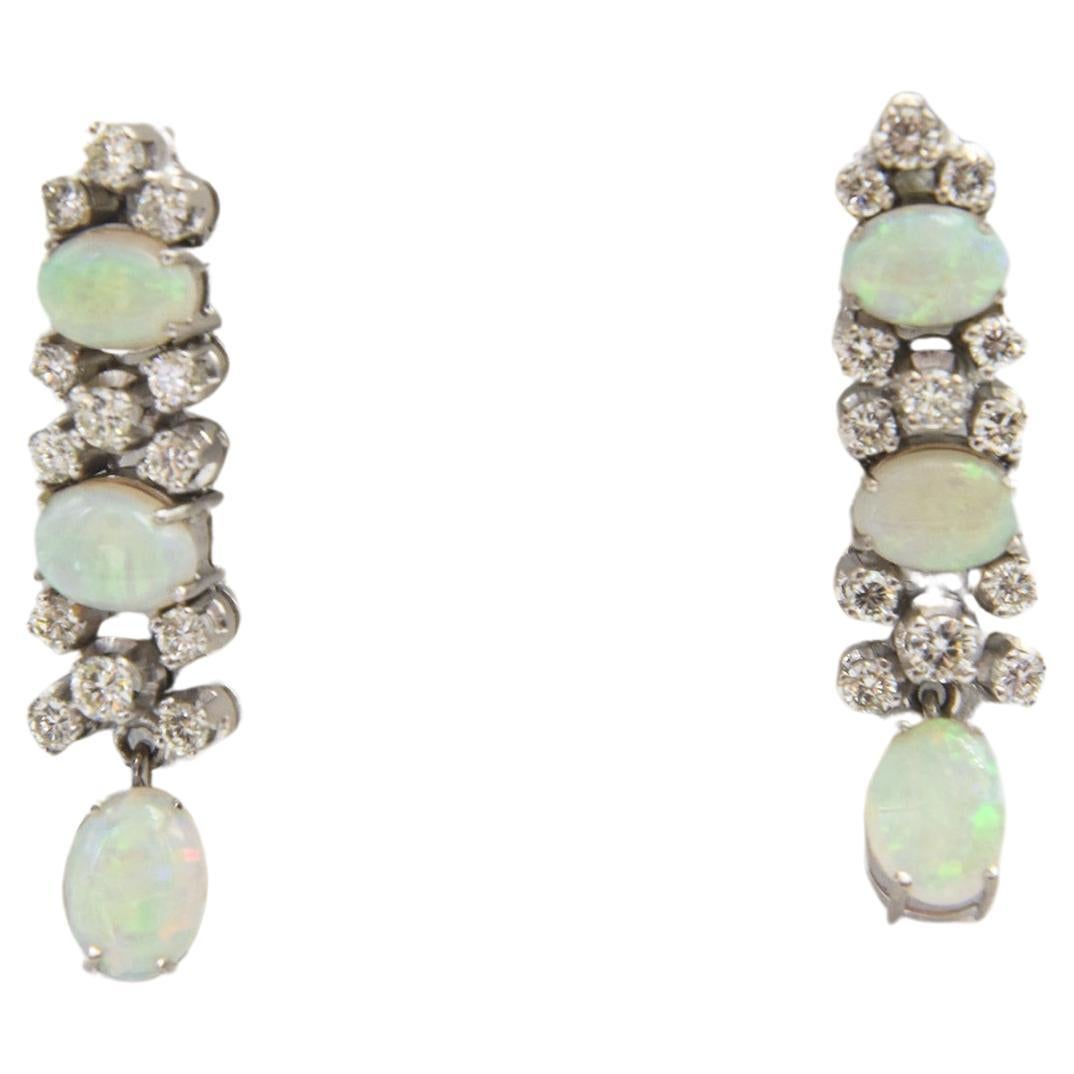 Custom made in the 1970s for an opal collector to highlight her beautiful Australian opals.  These 18k white gold earrings feature three graduating in size oval opals in each earring accented with round diamonds.  The opals have a crystal body with