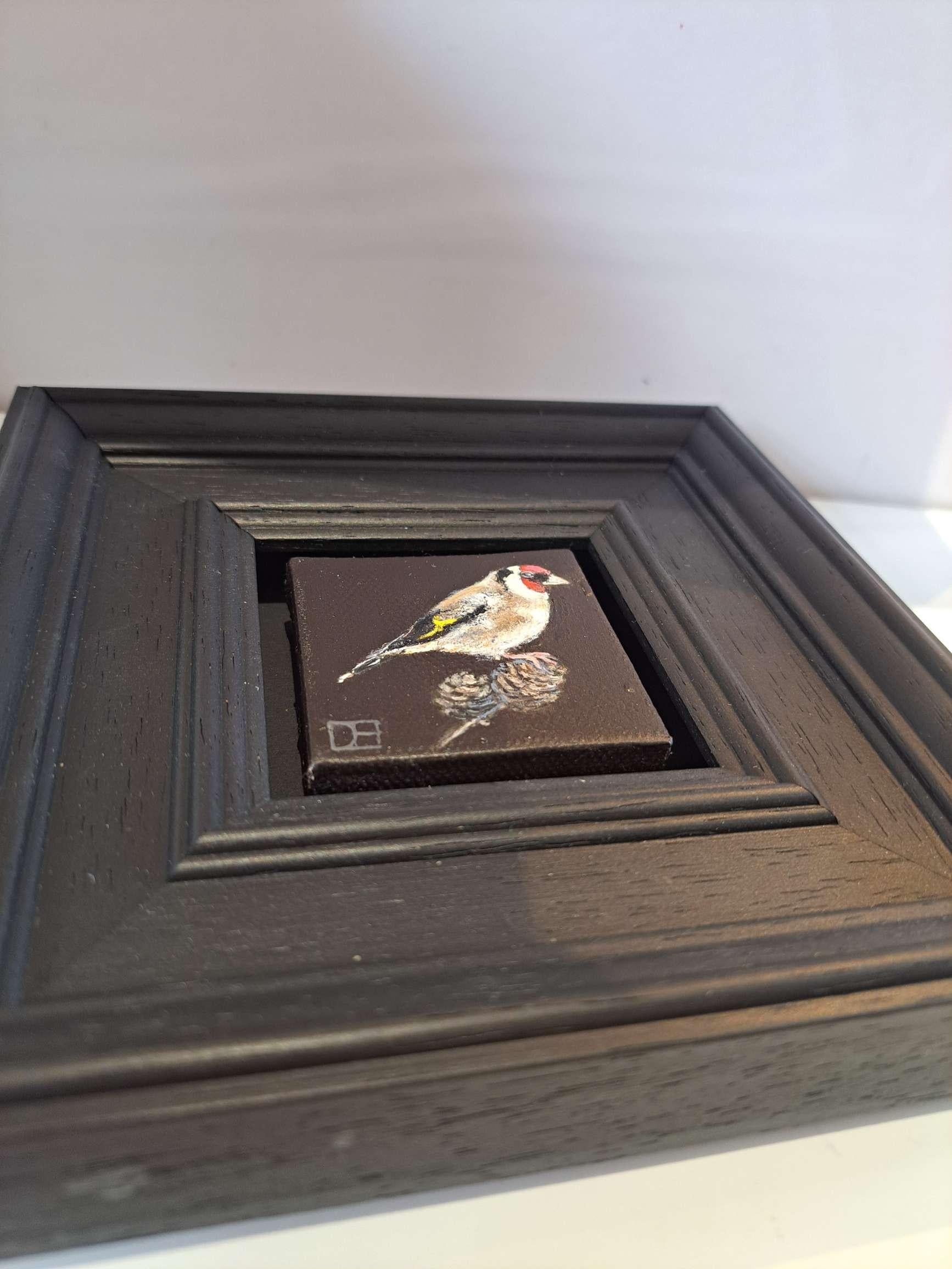 Pocket Goldfinch (Leinwandgröße 5x5cm) ist ein Original-Ölgemälde von Dani Humberstone als Teil ihrer Pocket Painting-Serie, die realistische Ölgemälde in kleinem Maßstab mit einer Anspielung auf die barocke Stilllebenmalerei umfasst. Die Gemälde