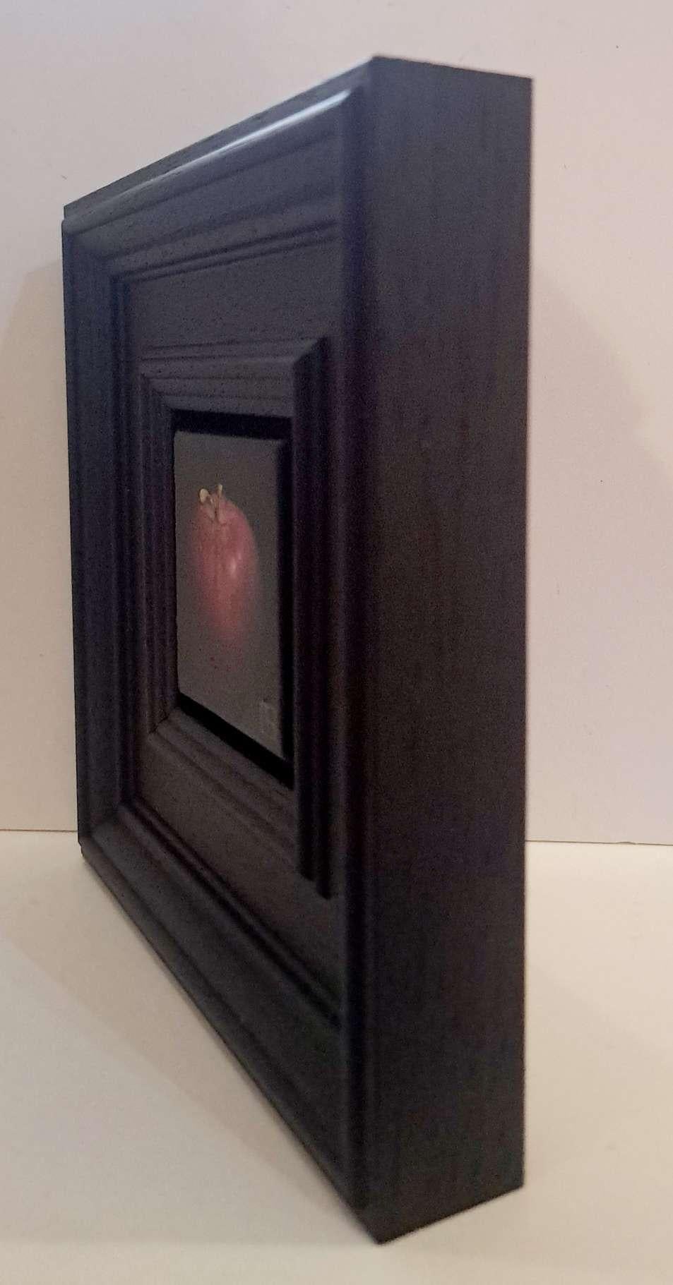 Pocket Deep Red Apple c es un óleo original de Dani Humberstone que forma parte de su serie Pocket Painting, que presenta óleos realistas a pequeña escala, con un guiño a la pintura barroca de bodegones. Los cuadros están colocados en un marco de