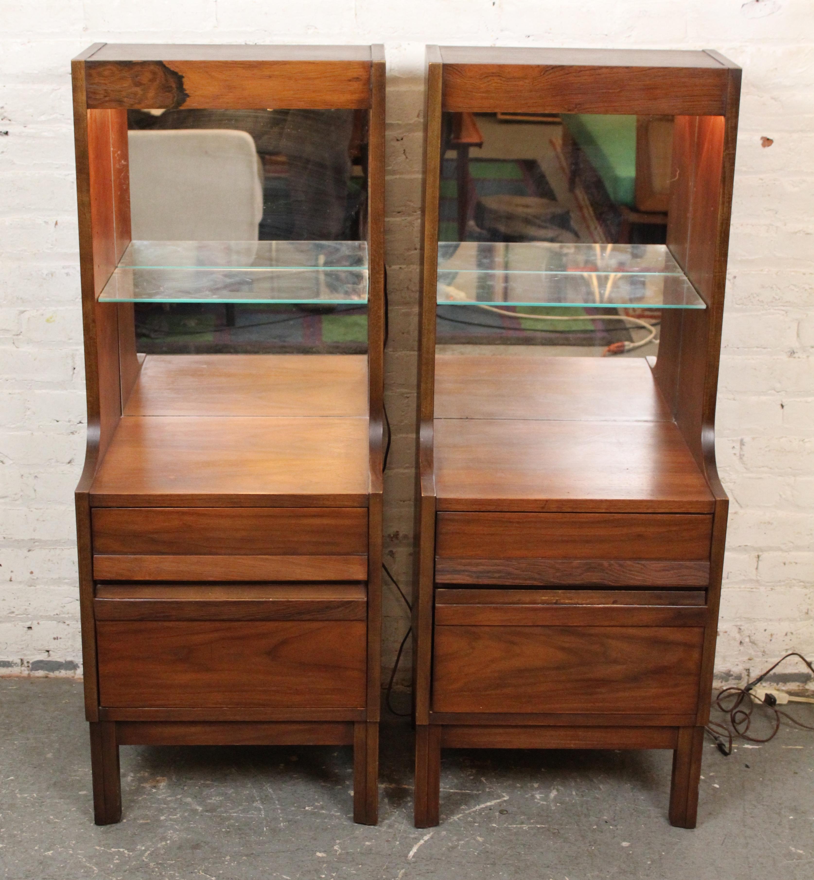 Pareja de mesitas librería con iluminación superior de American of Martinsville para su serie Dania 3. En nogal cálido con palisandro exótico, fondo de espejo y tiradores de madera incrustados. 
Por favor, confirme la ubicación NY o NJ