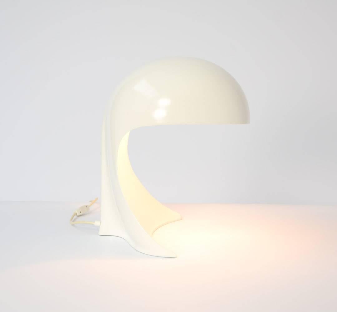 The Dania table lamp was designed by Dario Tognon in collaboration with Studio Celli for Artemide in 1969. It is a high quality table lamp, a sculptural design.
This elegant cobra-like lamp is made of one piece in white coated aluminium. One of the
