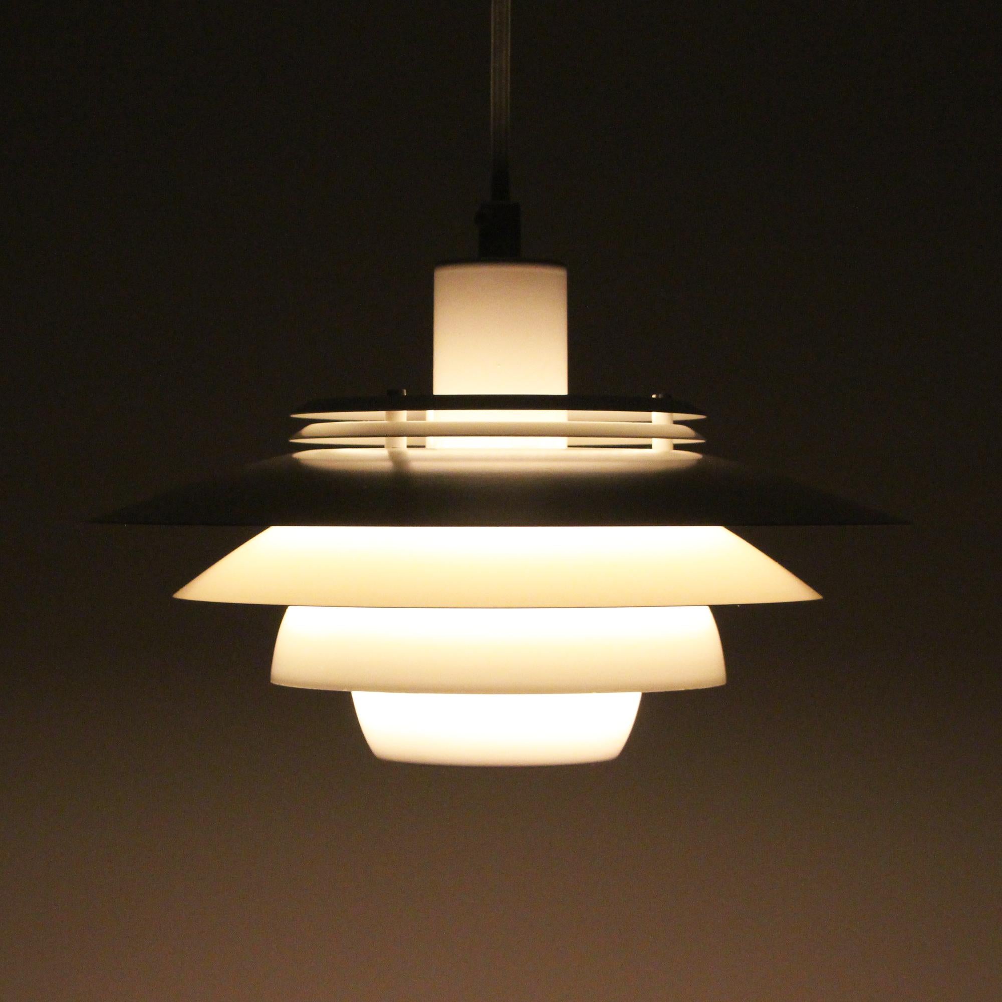 Dania, No. 2030 white lamp by Danish Jeka Metaltryk in the 1980s, stylish white hanging lamp in good vintage condition.

A Minimalist pendant light with 4 circular white metal shades, placed on white lacquered metal 'spacers' at a narrow distance