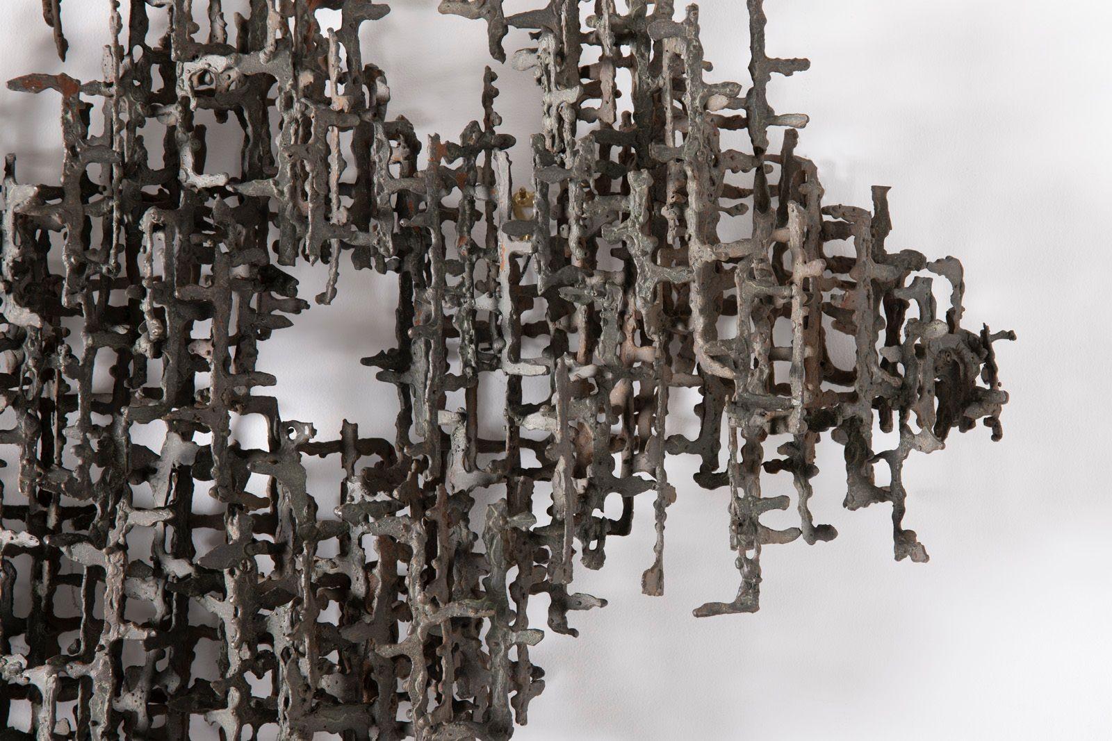 Diese großformatige, an der Wand montierte Skulptur von Dan Gluck ist ein beeindruckendes Beispiel brutalistischer Kunst. Sie besteht aus kunstvoll geschweißten Stahlelementen, die in einer dynamischen abstrakten Komposition angeordnet sind. Das
