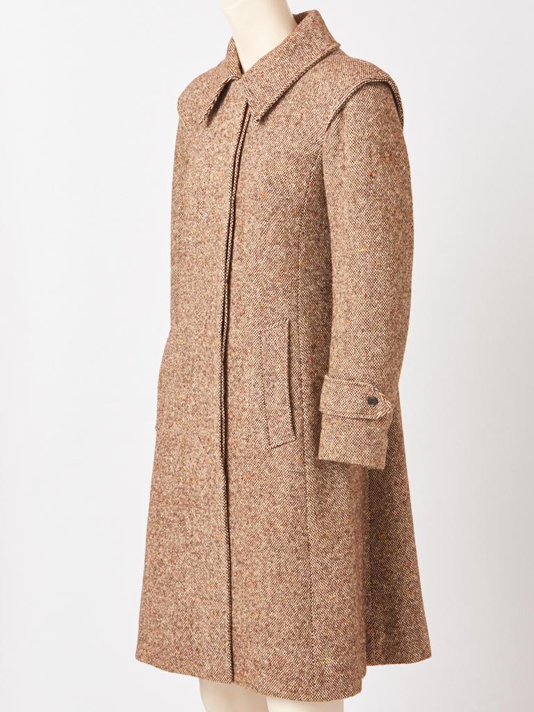Daniel Hechter, rust tone, wool, Donegal tweed, fitted A line coat, having a pointed collar, hidden front button closures, slash pockets and a deep inverted middle back pleat with vertical button detail. The coat was made in France for the NY store,