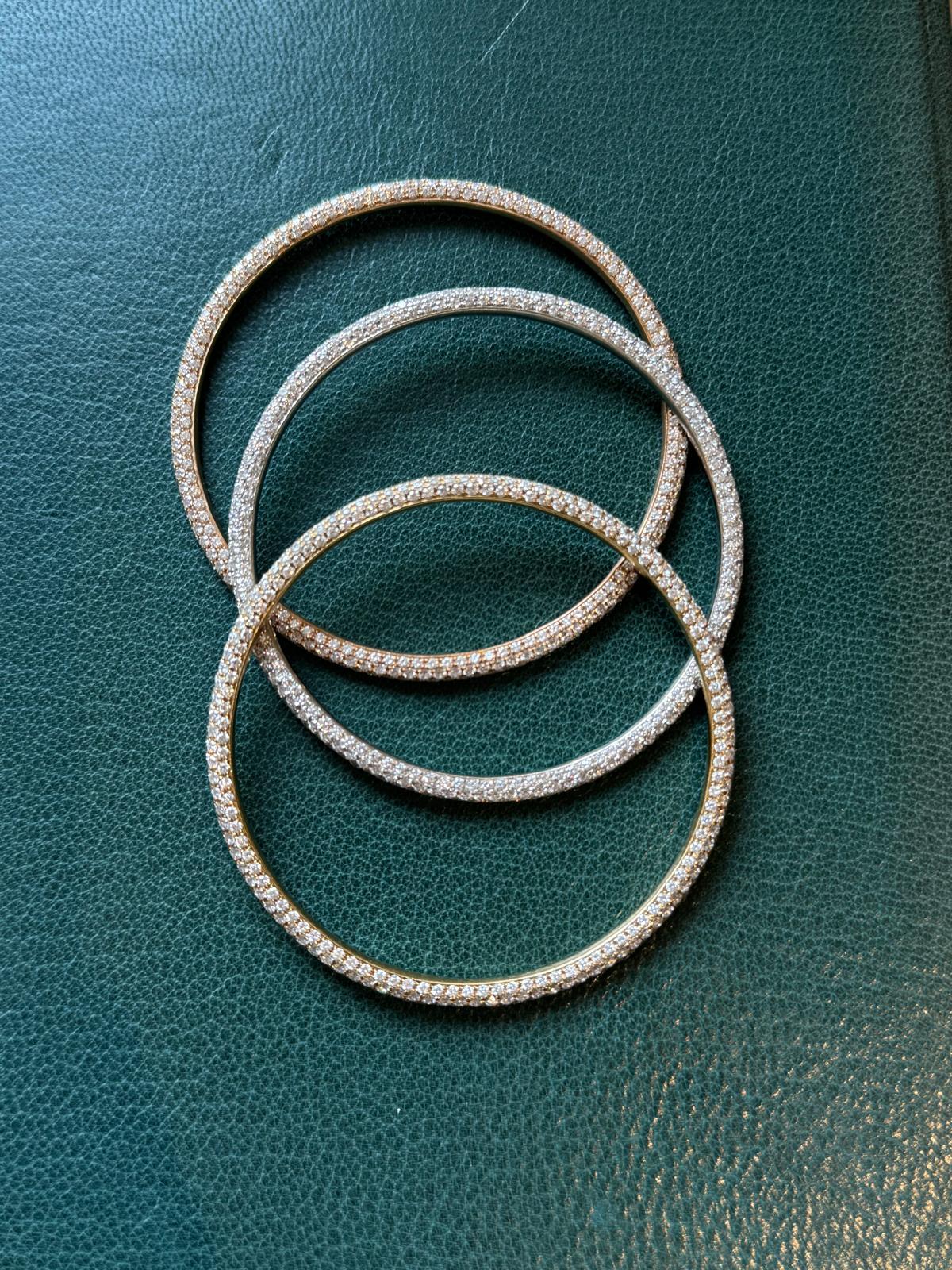 Three bangle bracelets signed by Daniel K, one in yellow gold, one in rose gold and grey gold. All three are signed and have the hallmark 18k. 

The yellow gold bracelet weight is 22,30 g
The rose gold bracelet weight is 21 g
The grey gold bracelet