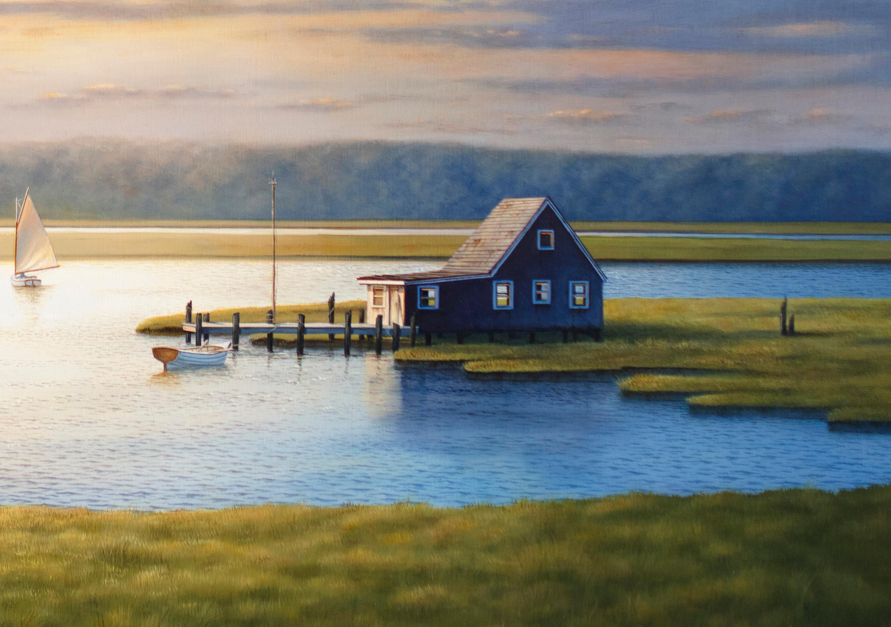 This contemporary realist painting by Daniel Pollera is a landscape of a Bay House in Long Island. The Bay House can be seen to the right, surrounded by water and marshy greenery, with one sailboat sailing by it and another closer to the horizon