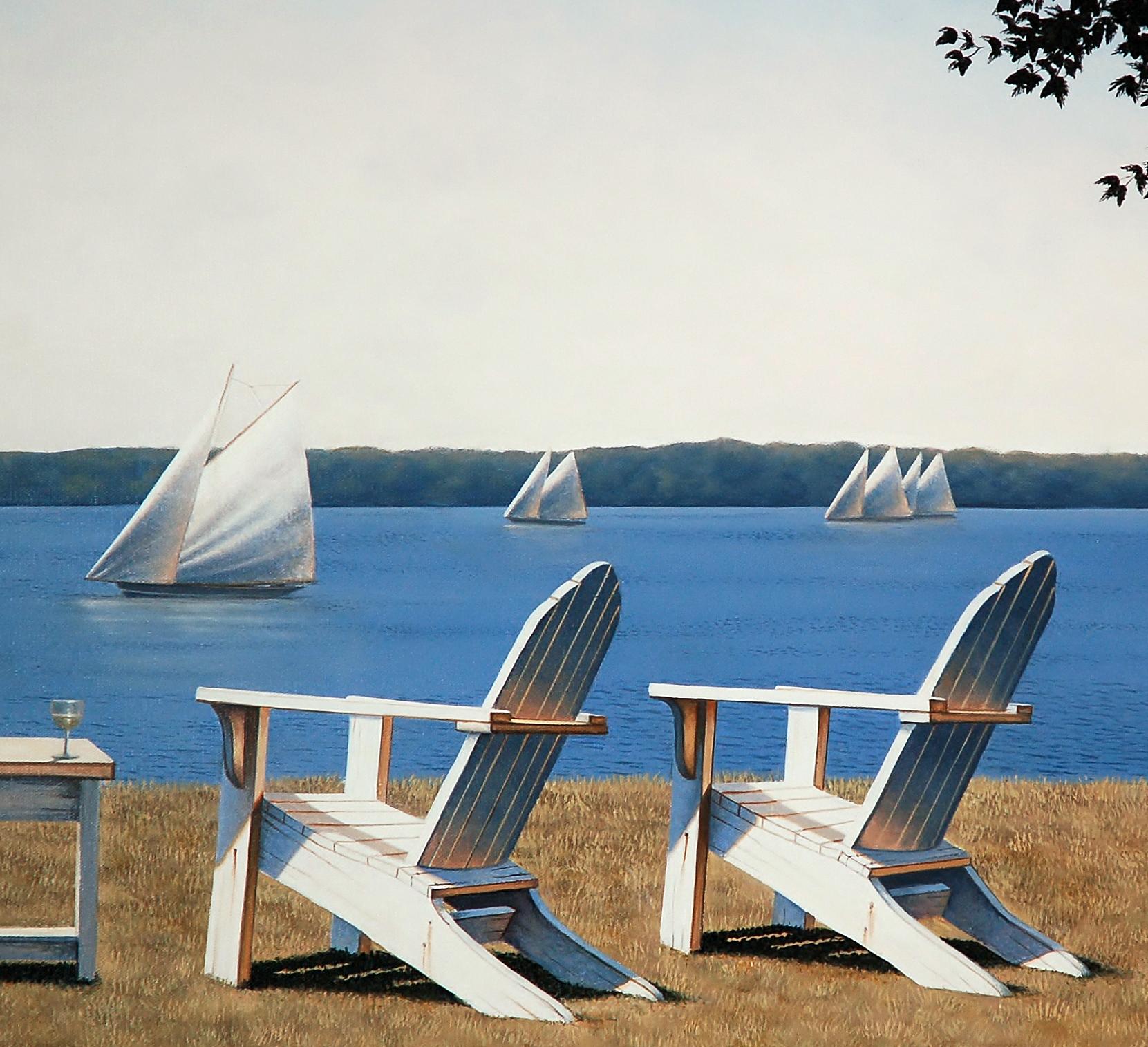 This traditional coastal Limited Edition print by Daniel Pollera pictures three white Adirondack chairs, positioned in the grass overlooking a body of water. Several sailboats can be seen close up and further out along the horizon line. A pale blue