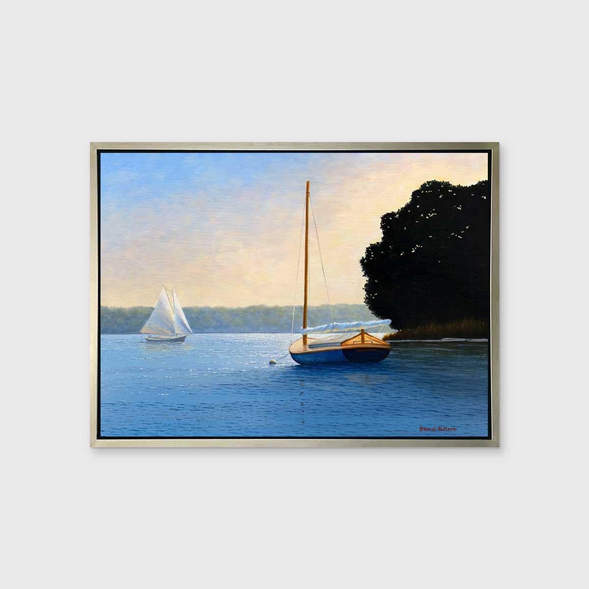 This traditional Limited Edition print by Daniel Pollera captures a coastal scene. A sailboat with its sail down sits in the shadow of dark trees, and looks out toward another white sailboat that is passing by. Above the green foliage that lines the