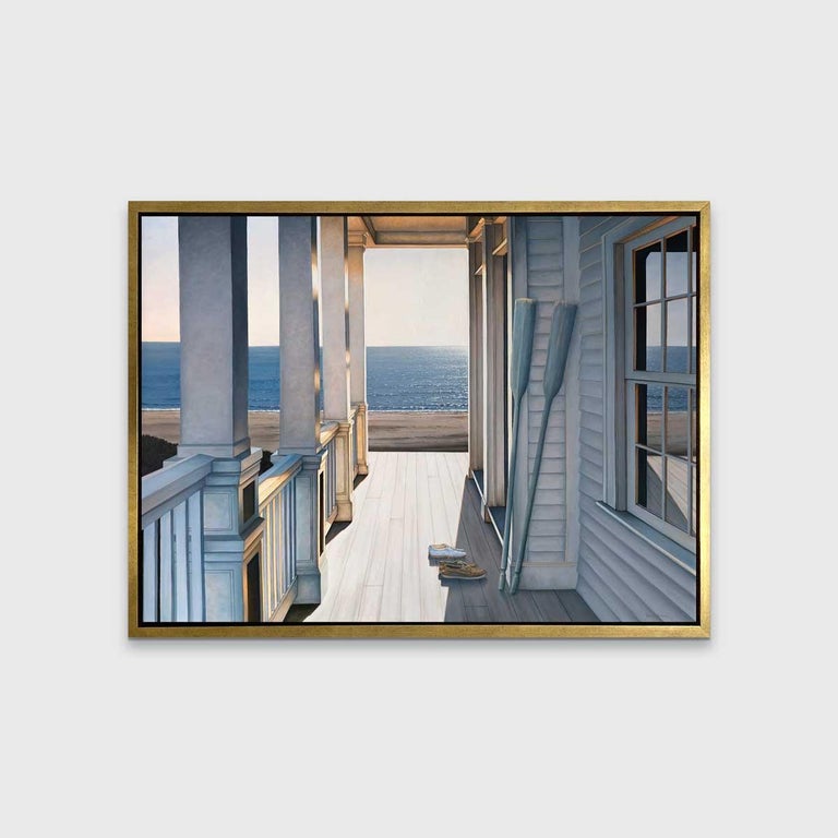 This coastal seascape limited edition print captures a scene from the porch of a beachfront property along the coast. A setting sun casts sharp light and cool blue-grey shadows across the porch, where two sets of shoes and two boat paddles rest