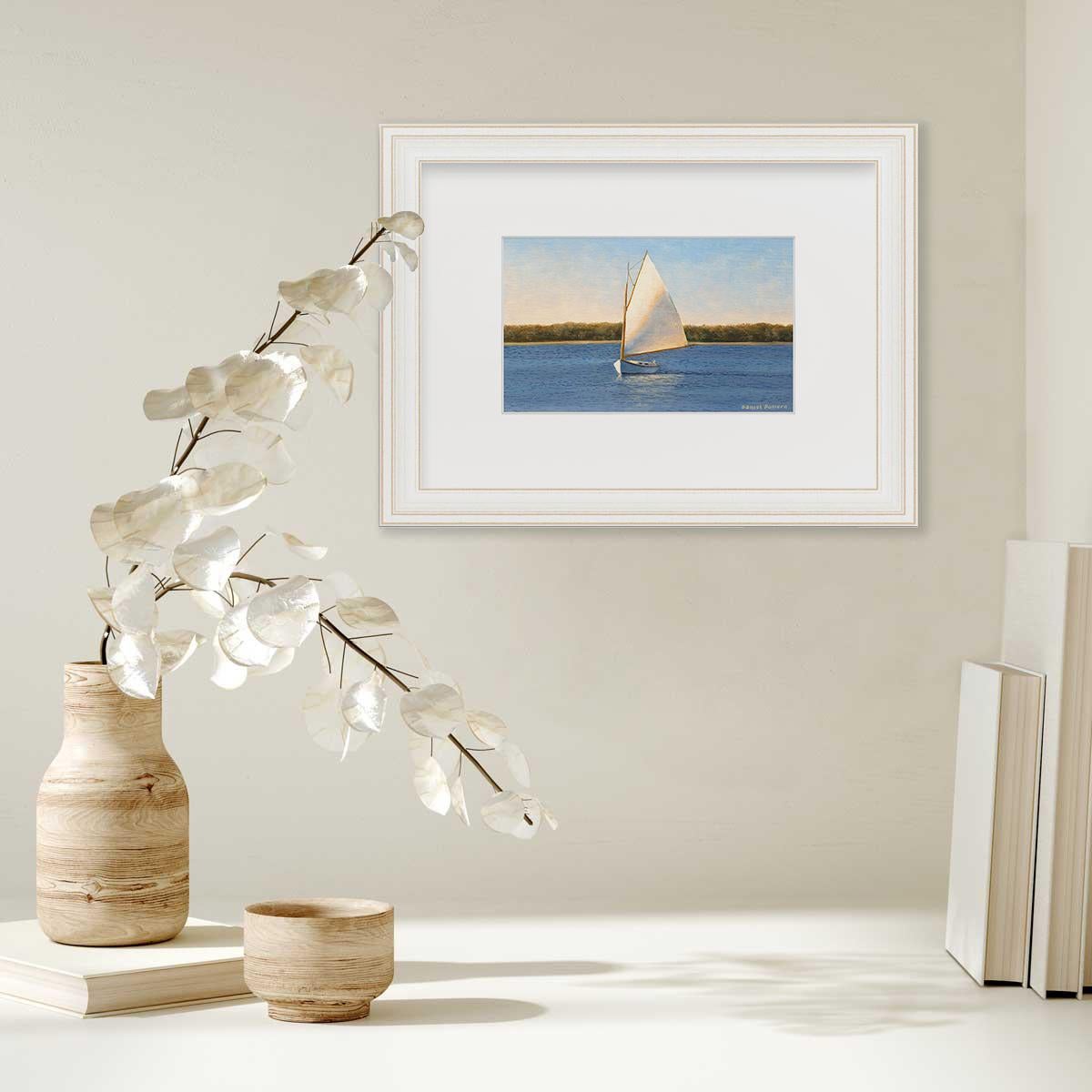 This limited edition print by Daniel Pollera features a small sailboat with a white sale, sailing along a coastline of green foliage behind it. The sun shines from the left hand side of the composition, so the white sale has a warm undertone. Above