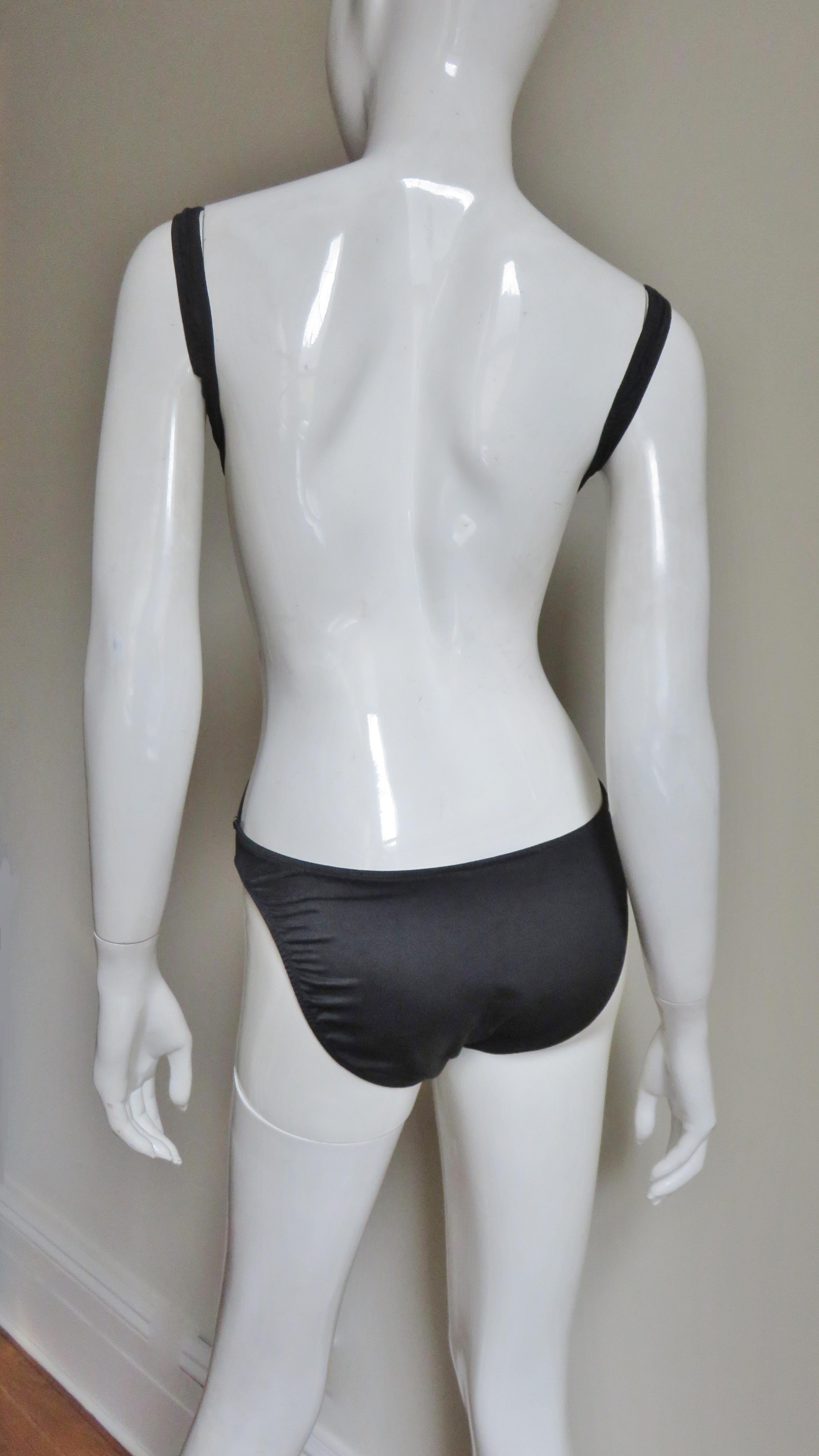 A fabulous black swimsuit from Daniel Storto.  It has front crossing gradated panels emanating from the sides of the bottoms covering the bust then wrapping around the shoulders and underarms. The back is bare except for the bottoms and 2 bands