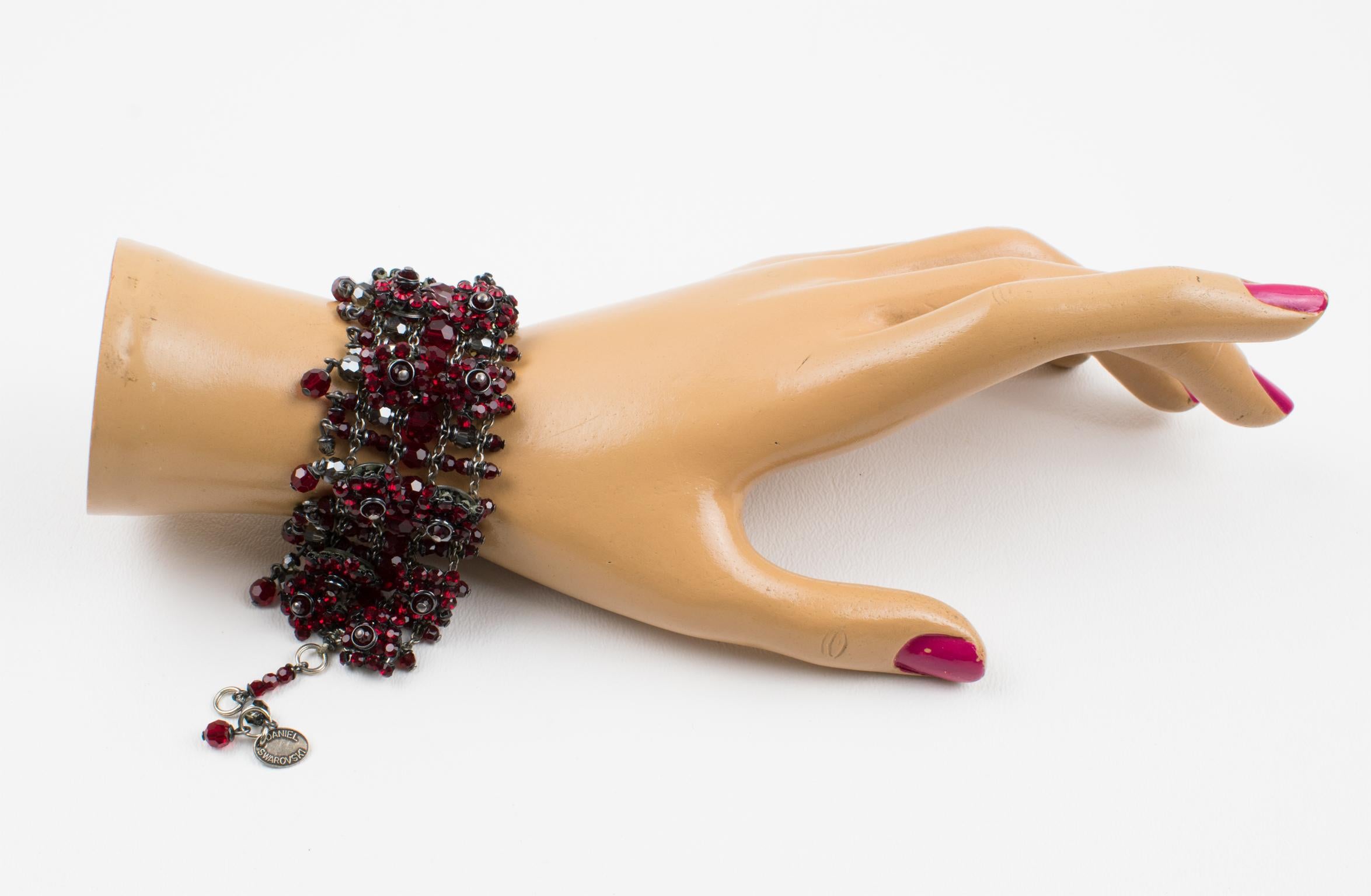 Cet élégant bracelet à maillons Daniel Swarovski Paris couture présente une forme articulée d'inspiration victorienne et des chaînes en métal argenté ornées de strass et de perles à facettes en cristal Swarovski rouge rubis et gris fumé. La pièce