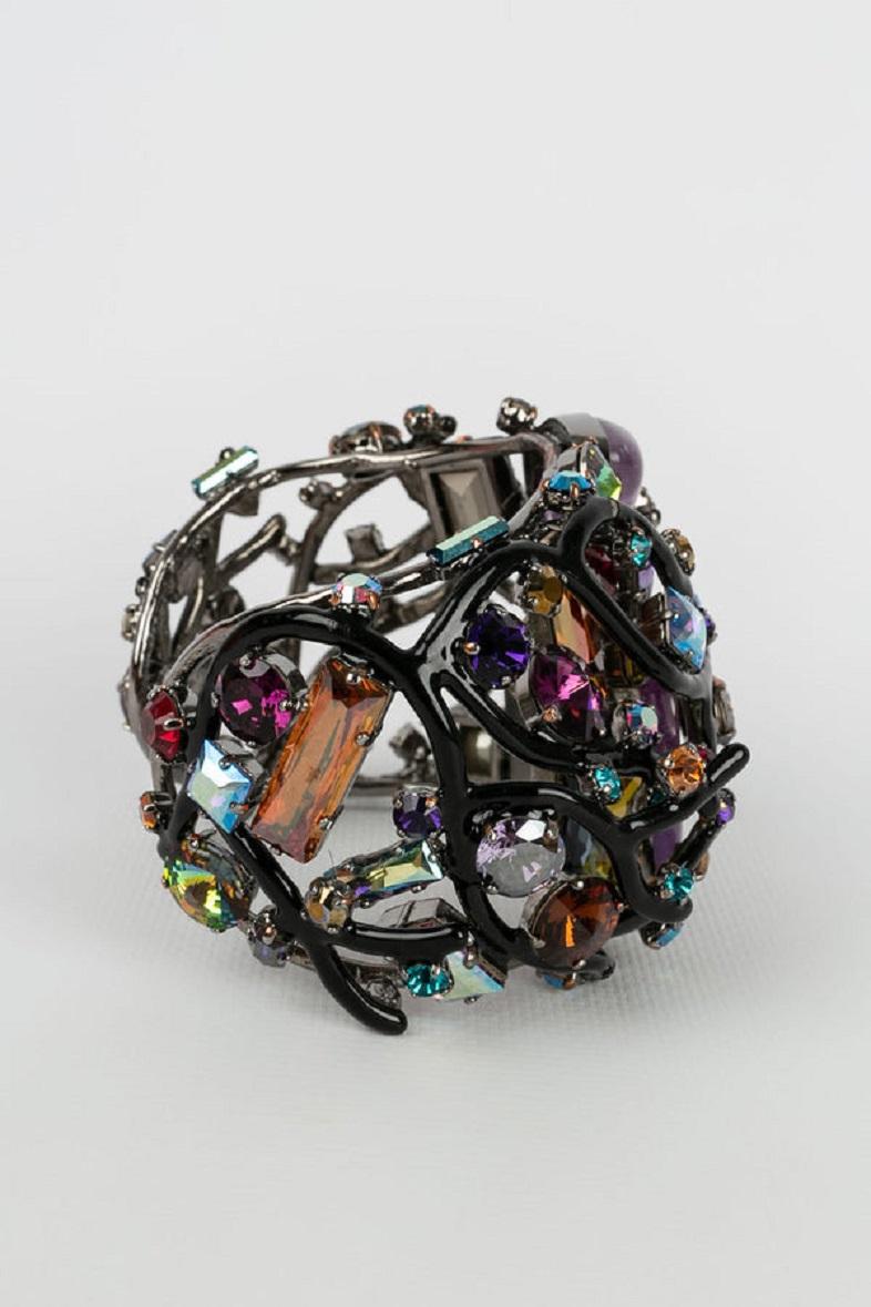 Swarovski -Openwork cuff in silver plated metal enamelled in black. It is paved with multicolored rhinestones and topped with two Amethysts.

Additional information:
Dimensions: Circumference: 18 cm 
Opening: 3 cm 
Width: 6 cm
Condition: Very good