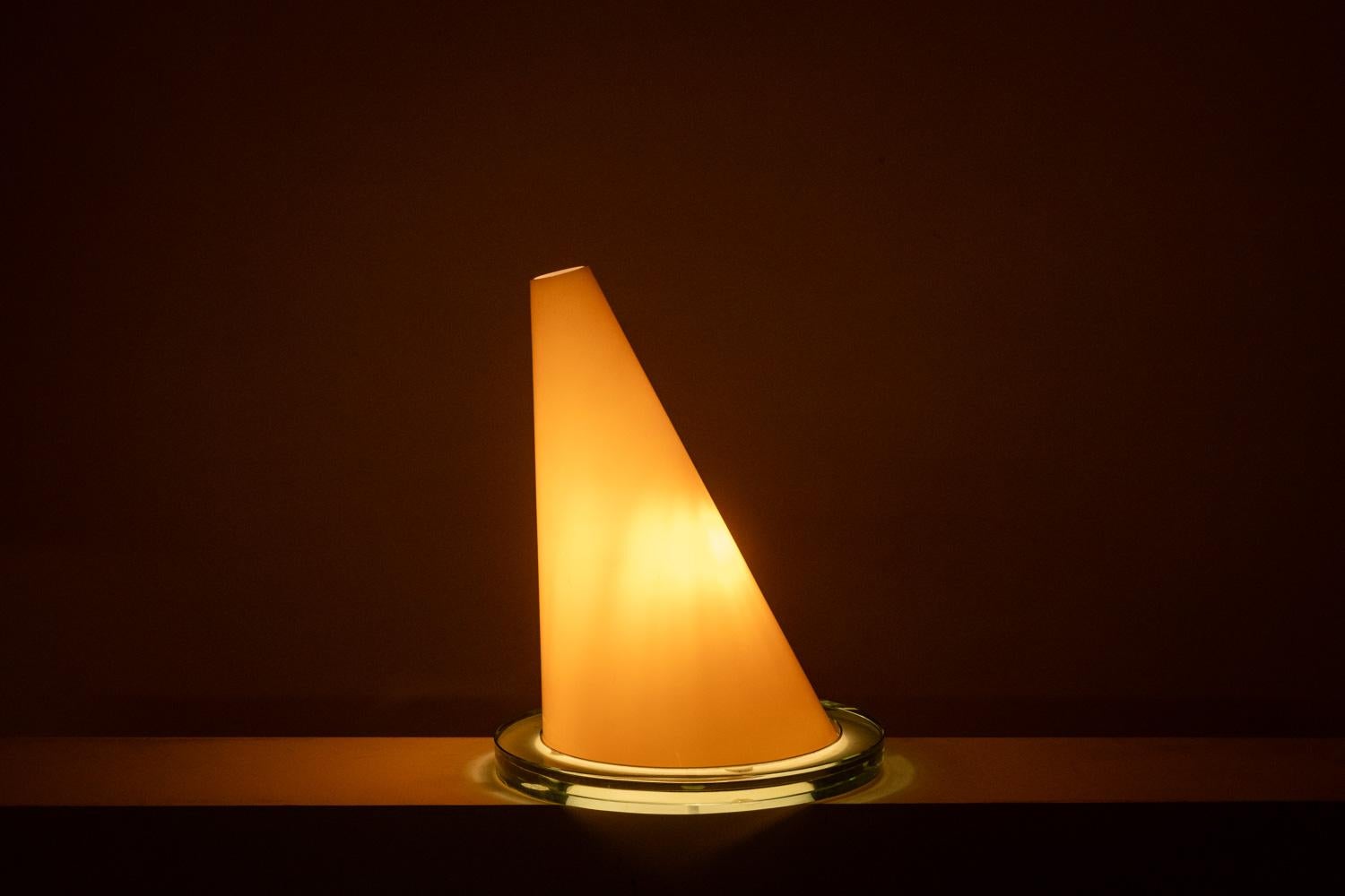 Daniela Puppa pour Fontana Arte.

Lampe en verre de Murano, composée d'un abat-jour de forme conique, de couleur orange, allusion au chapeau du magicien d'Oz, reposant sur une base de forme circulaire, de couleur transparente.

Œuvre italienne