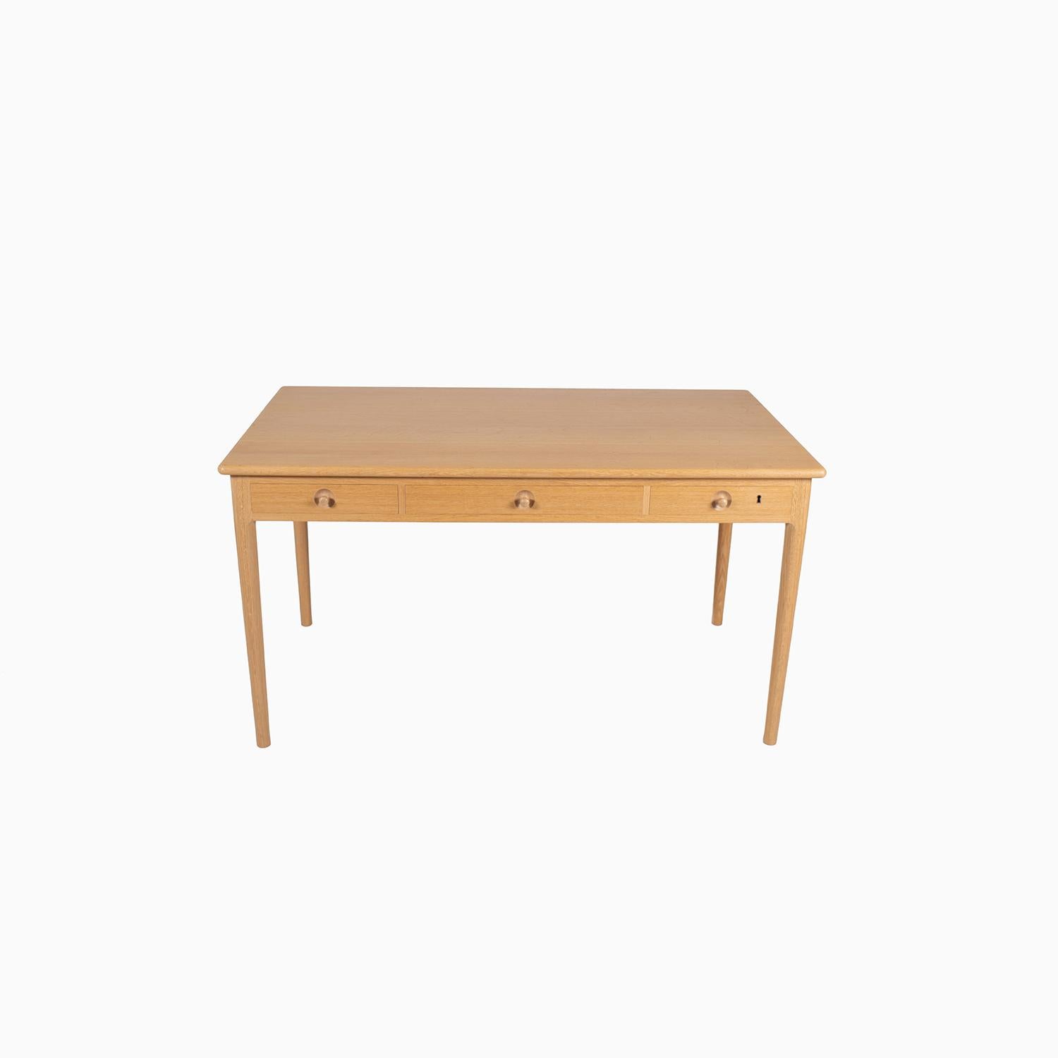 A writing desk in oak that exemplifies studio level woodworking. A design by Hans J. Wegner known as the “Classic Desk” which references traditional Scandinavian cabinetmaking. 
This example is a later model produced by PP Mobler. Three drawers with