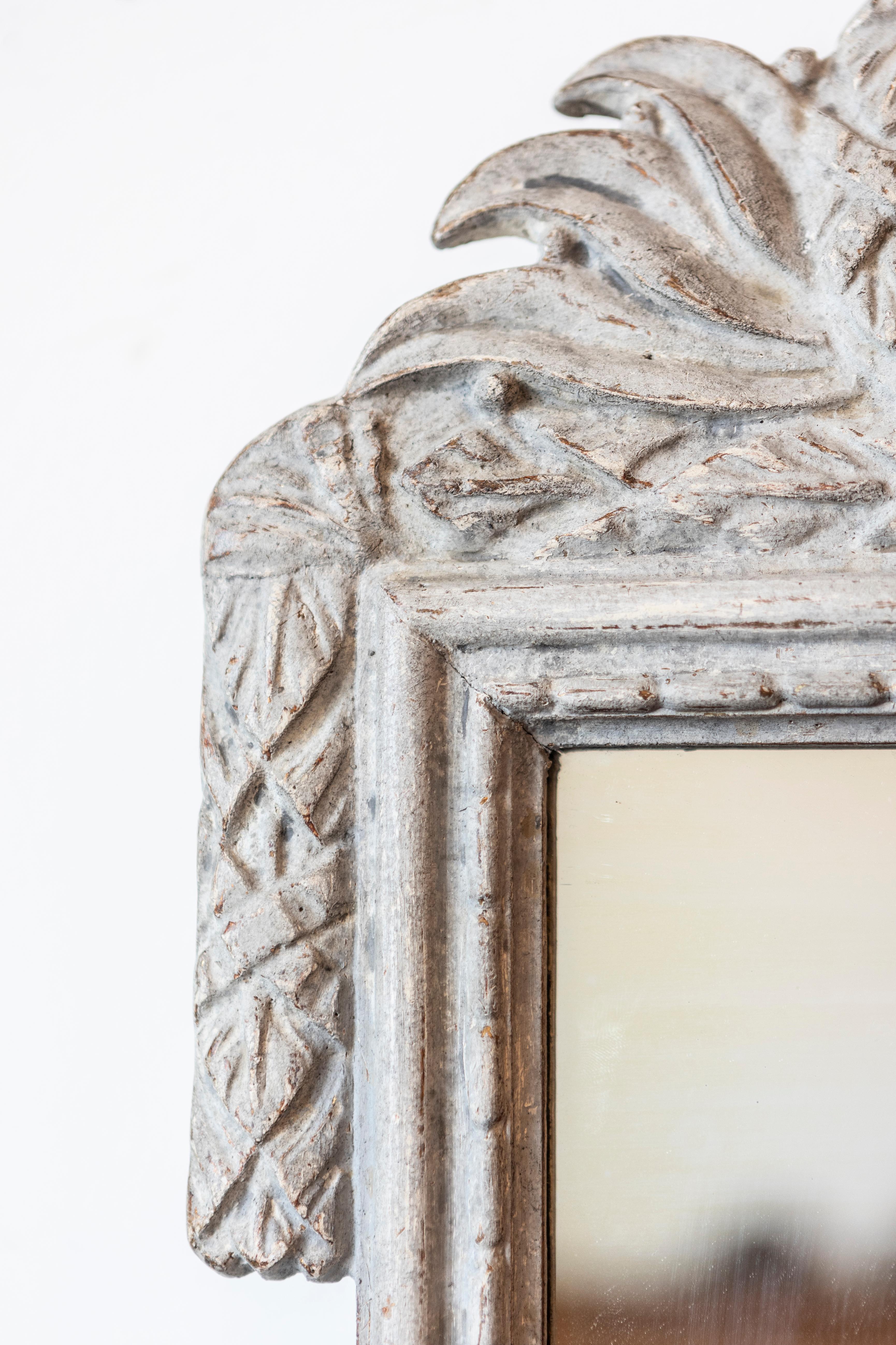 Ein dänischer grau bemalter Holzspiegel aus der Zeit um 1800 mit geschnitztem Wappen. Dieser exquisite dänische Spiegel aus bemaltem Holz aus der Zeit um 1800 zeigt die raffinierte Eleganz, die für seine Epoche charakteristisch ist. Der Spiegel ist