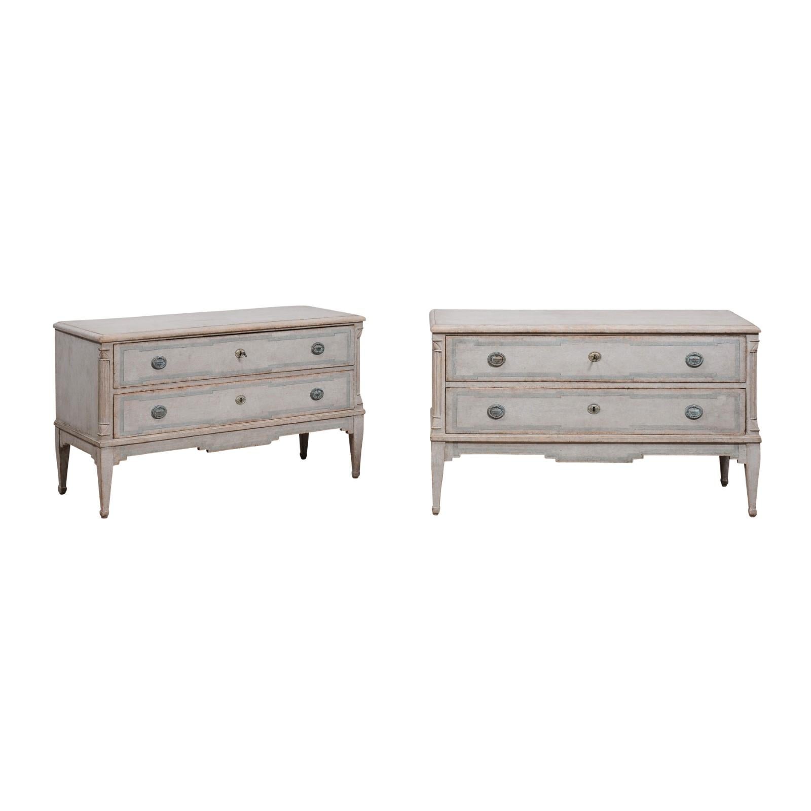 A pair of Danish two-drawer chests from circa 1820 with light gray painted finish, carved fluted semi-columns, tapered legs and painted trim on the drawers. Embrace the understated elegance of Danish design with this exquisite pair of two-drawer