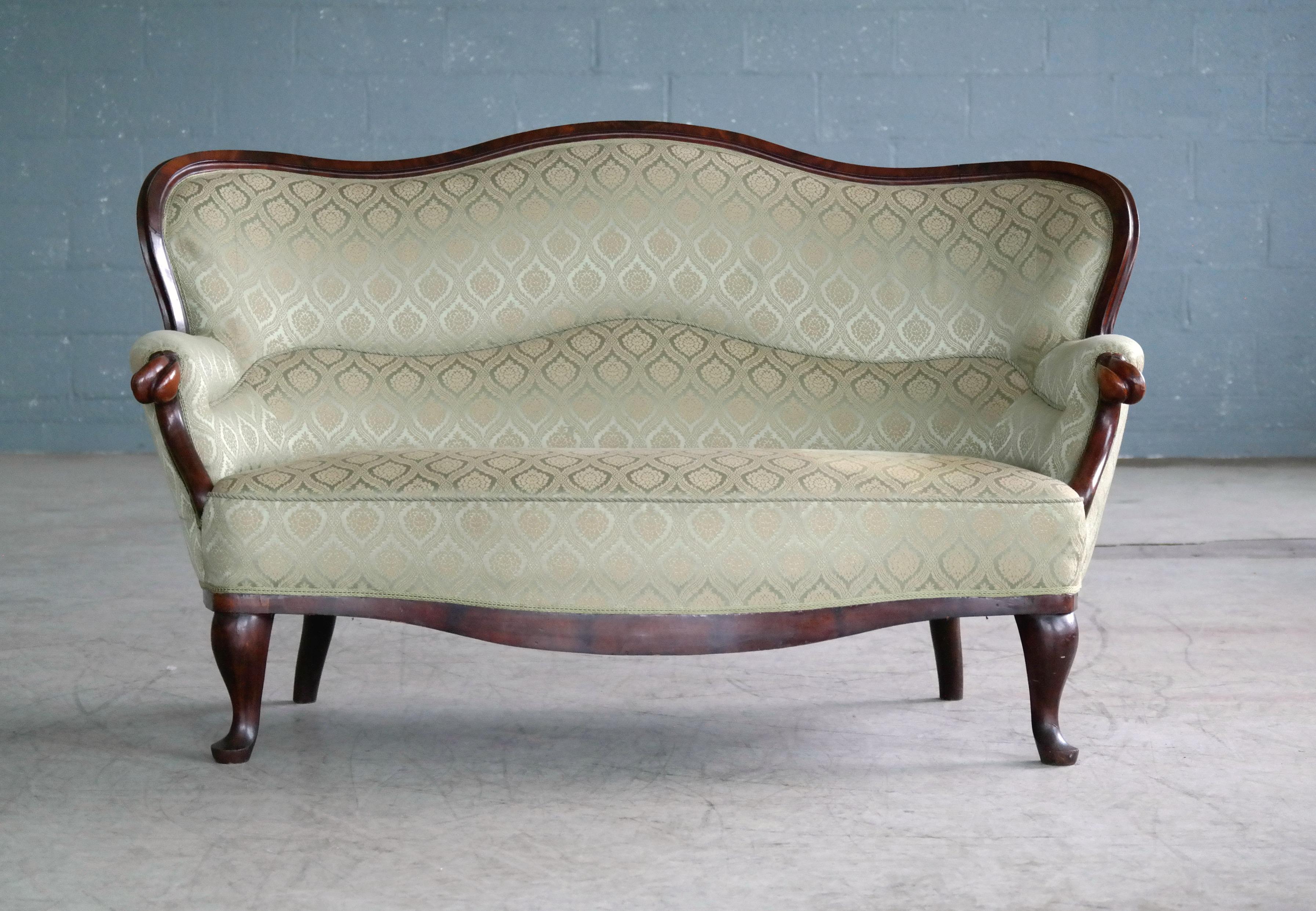 Elegantes Sofa im Stil des Rokoko-Revivals aus geschnitztem Mahagoni, hergestellt in Dänemark in den 1860er Jahren. Stabil und bequem mit nur kleinen Schrammen und Dellen am Holzrahmen und den Beinen. Der Stoff weist einige Verschmutzungen auf und