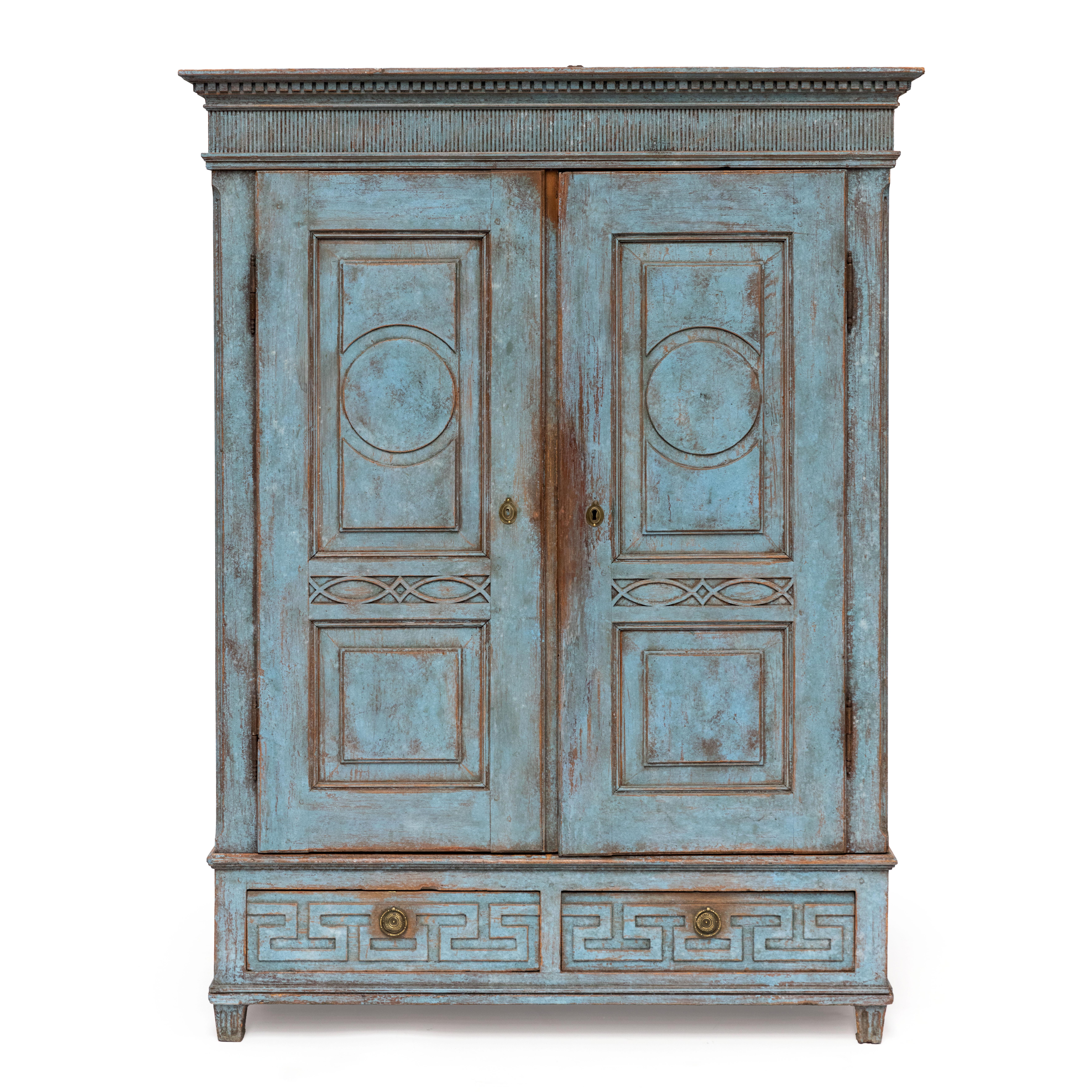 Elegante armario danés Luis XVI en un precioso color azul con gran pátina.

Presenta excepcionales detalles originales tallados en madera, como una cornisa con friso dentil y acanaladuras. Las puertas están adornadas con paneles arquitectónicamente