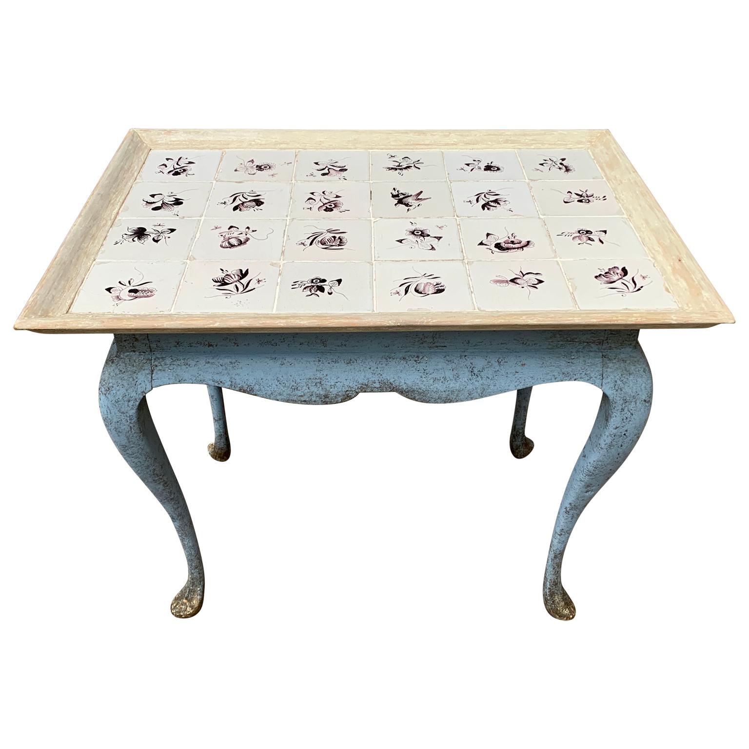 A Scandinavian Rococo blue painted pine console tile table with curved legs from end of 18th Century. The flower decorated tiles on the top are made in the Netherlands and are hand painted in manganese color. 
This table is in good sturdy and