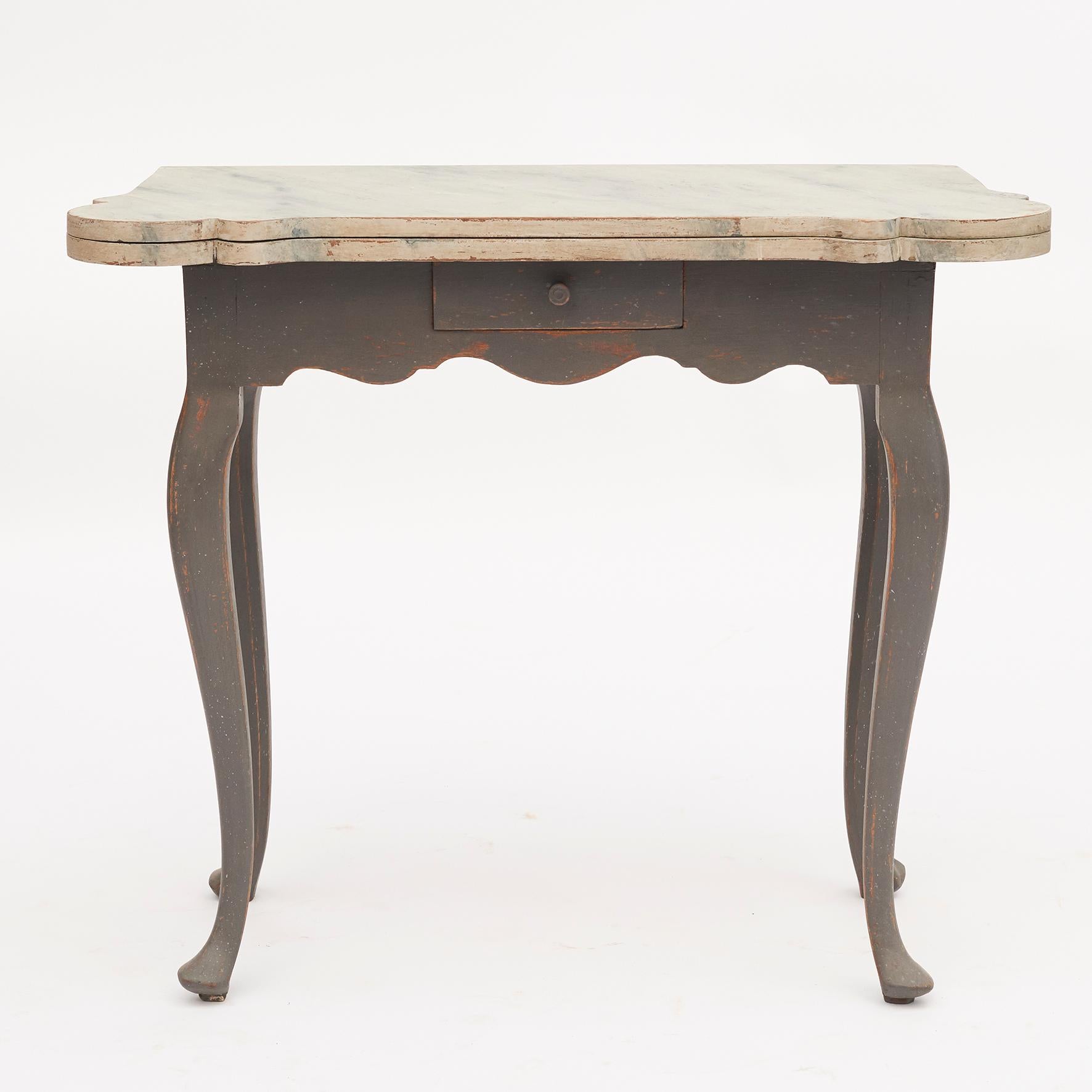 Dänischer Rokoko-Konsolen- und Spieltisch aus dem 18. Jahrhundert. Der Deckel lässt sich anheben und gibt den Blick auf das Innere mit Kerzenständern und Perlenketten frei.
Tisch von rechteckiger Form, wenn er geschlossen ist, mit vier