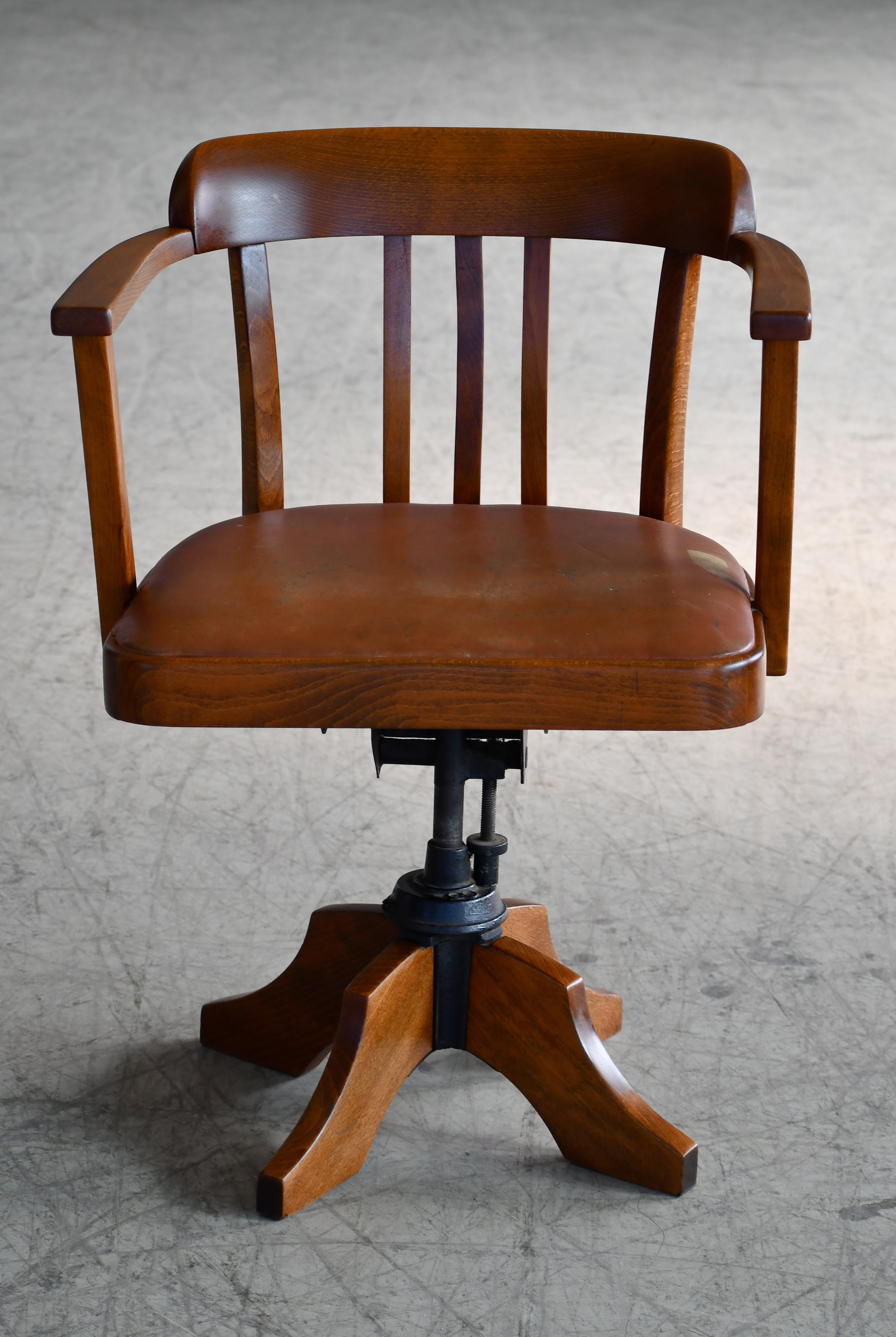 1920's swivel desk chair in leather and solid oak. It is rare to find these very cool and solid chairs with a leather seat and even more so a leather seat that is still fully intact and in this good condition. The leather seat is showing nice wear