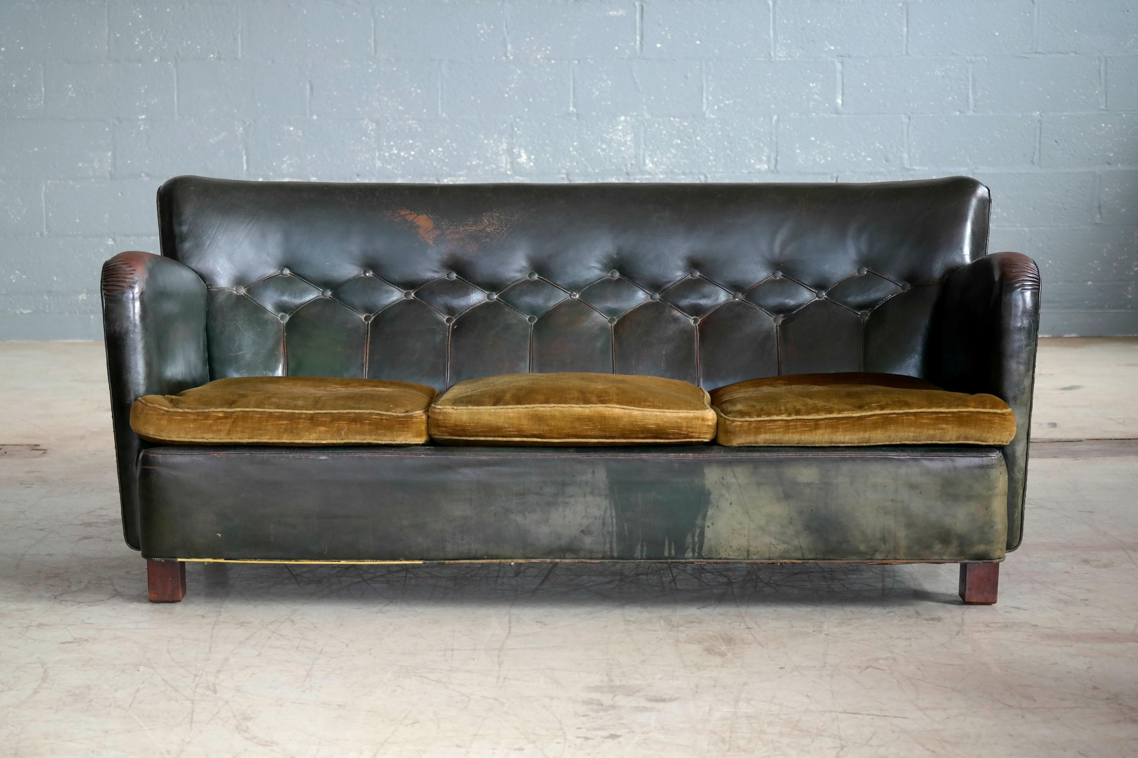 Rare Danish club sofa in green leather with tufted back and seats in a greenish yellow mohair fabric in the style of Flemming Lassen produced in Denmark likely around the mid-1930s. Legs made from solid mahogany. Comfortable and super solid in