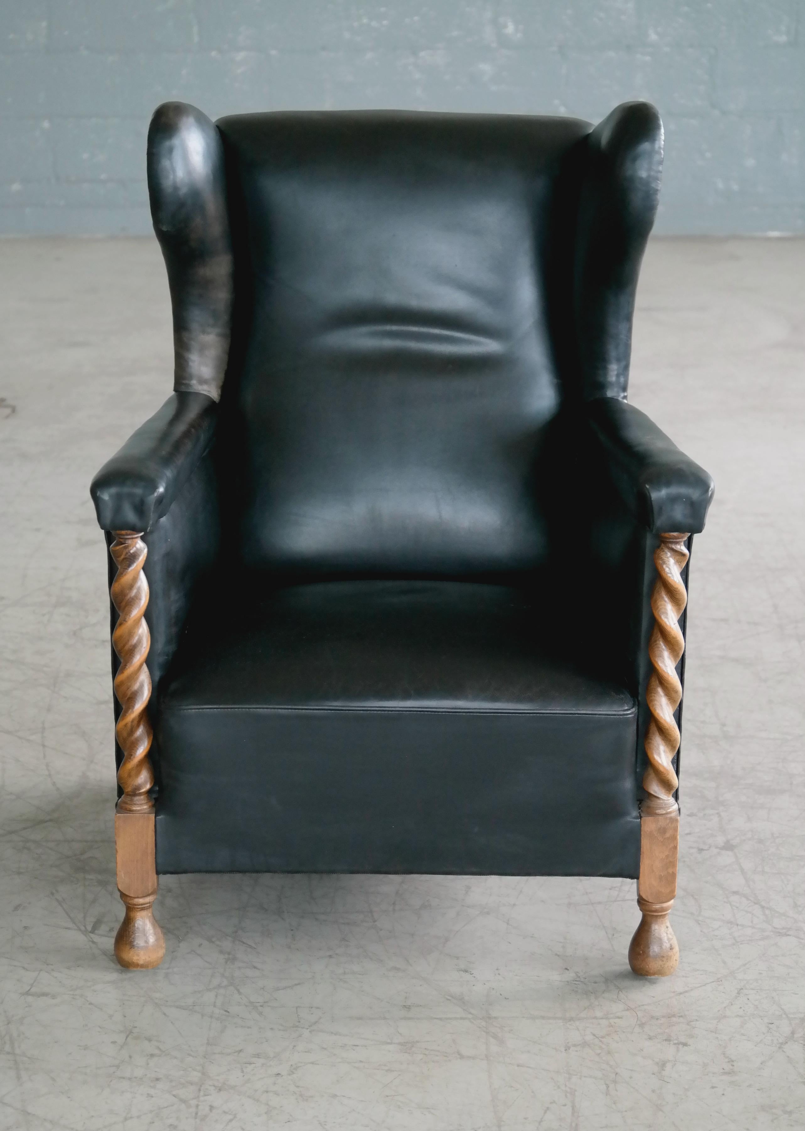Rare and very cool Danish Large scale club chair from the post Art Deco period of the mid to late 1930s. Fantastic patinated original black leather with hand carved uprights and front legs carved in solid oak. The use of solid oak is a good