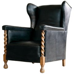 Danish 1930s Large Scale Club or Wingback Chair in Black Leather and Carved Oak