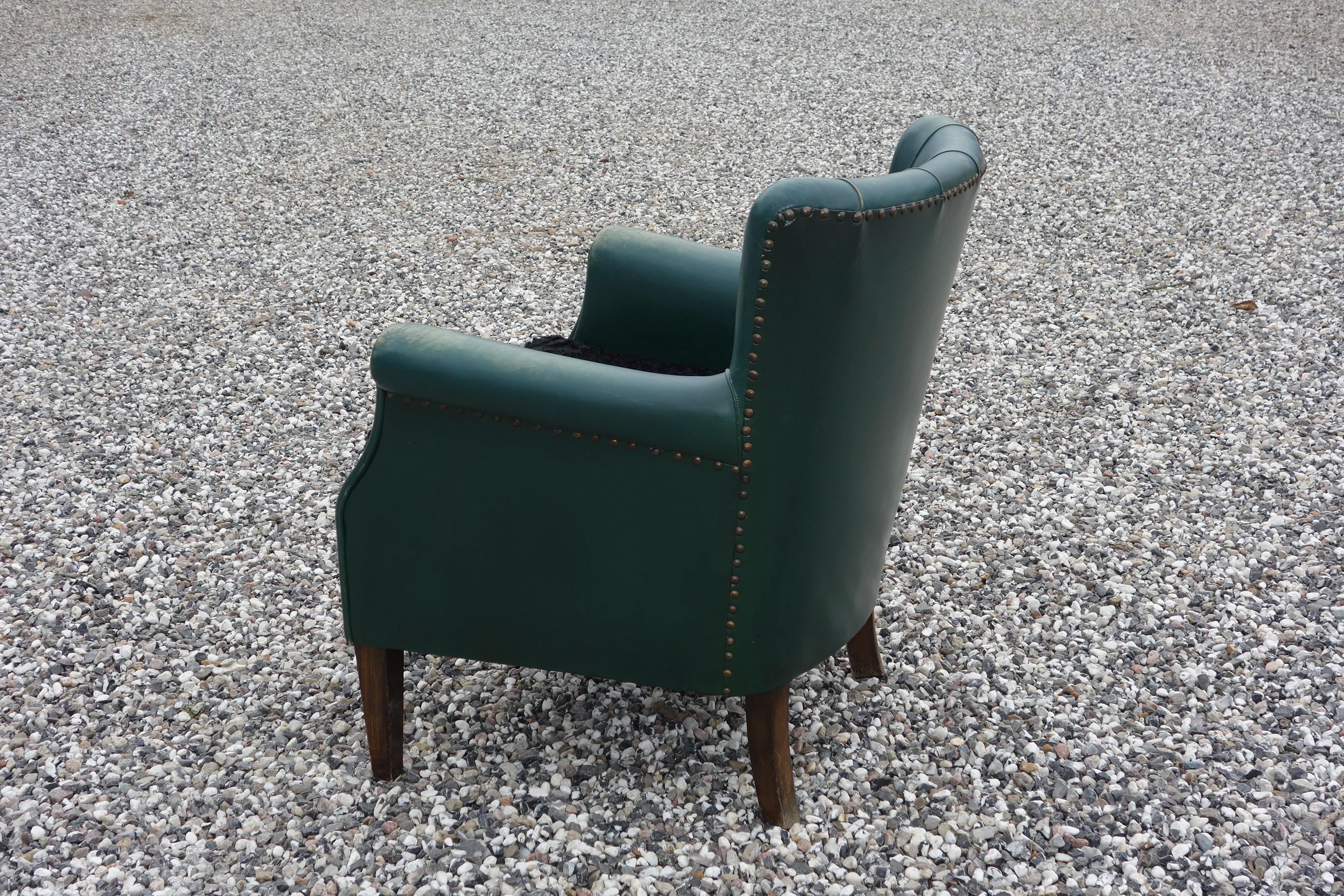 A 1930s Danish club chair with green leather. Pillow in black lambswool. Fine and ready to use condition.