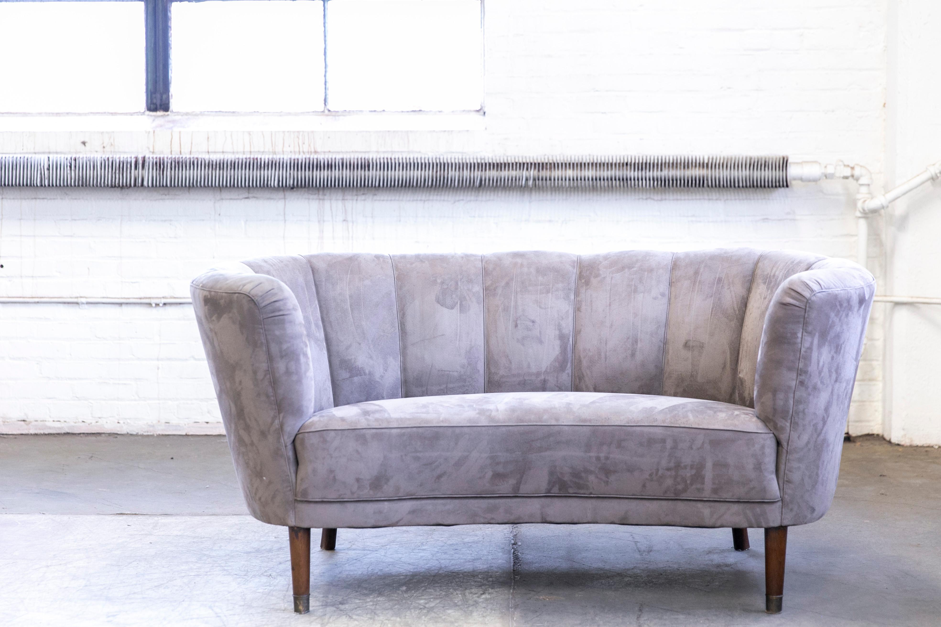 Beautiful and very elegant 1940s curved two-seat. The sofa has springs in the seat and the backrest and the cushions are nice and firm and the sofa very sturdy. The sofa was re-upholstered at a later point and the grey ultrasuede fabric is in still