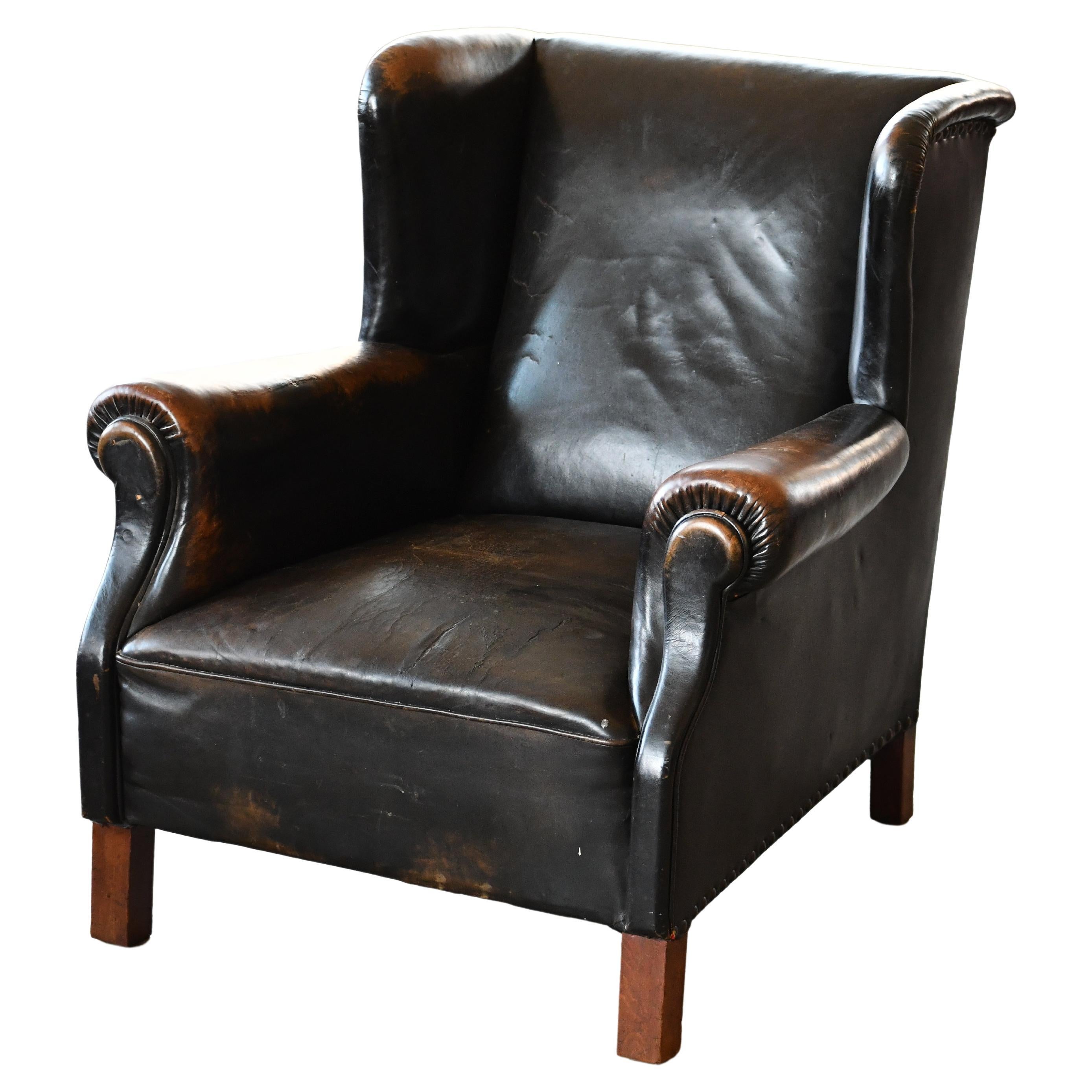 A rare find. Large wingback lounge chair in black leather. Maker unknown but the chair is much in the style of the Fritz Hansen chairs at the time. The leather remains supple and in unusual good condition for its age with lots of noble patina and