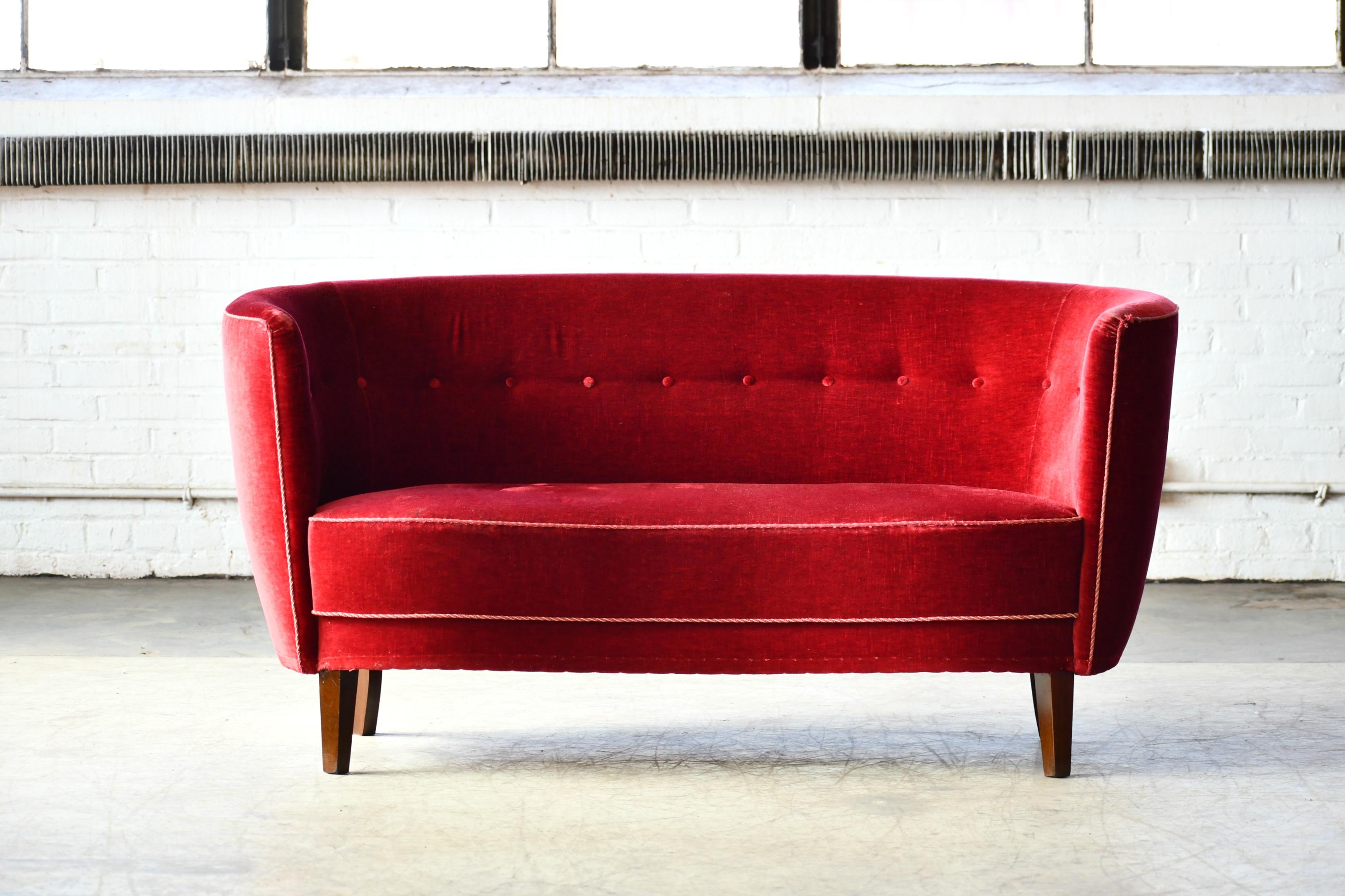 Beautiful and very elegant Danish 1940s curved two-seat sofa in red mohair wool raised on a beech frame and legs. Solid construction with springs in the seat and the backrest for support and cushioning. The sofa was re-upholstered in recent years