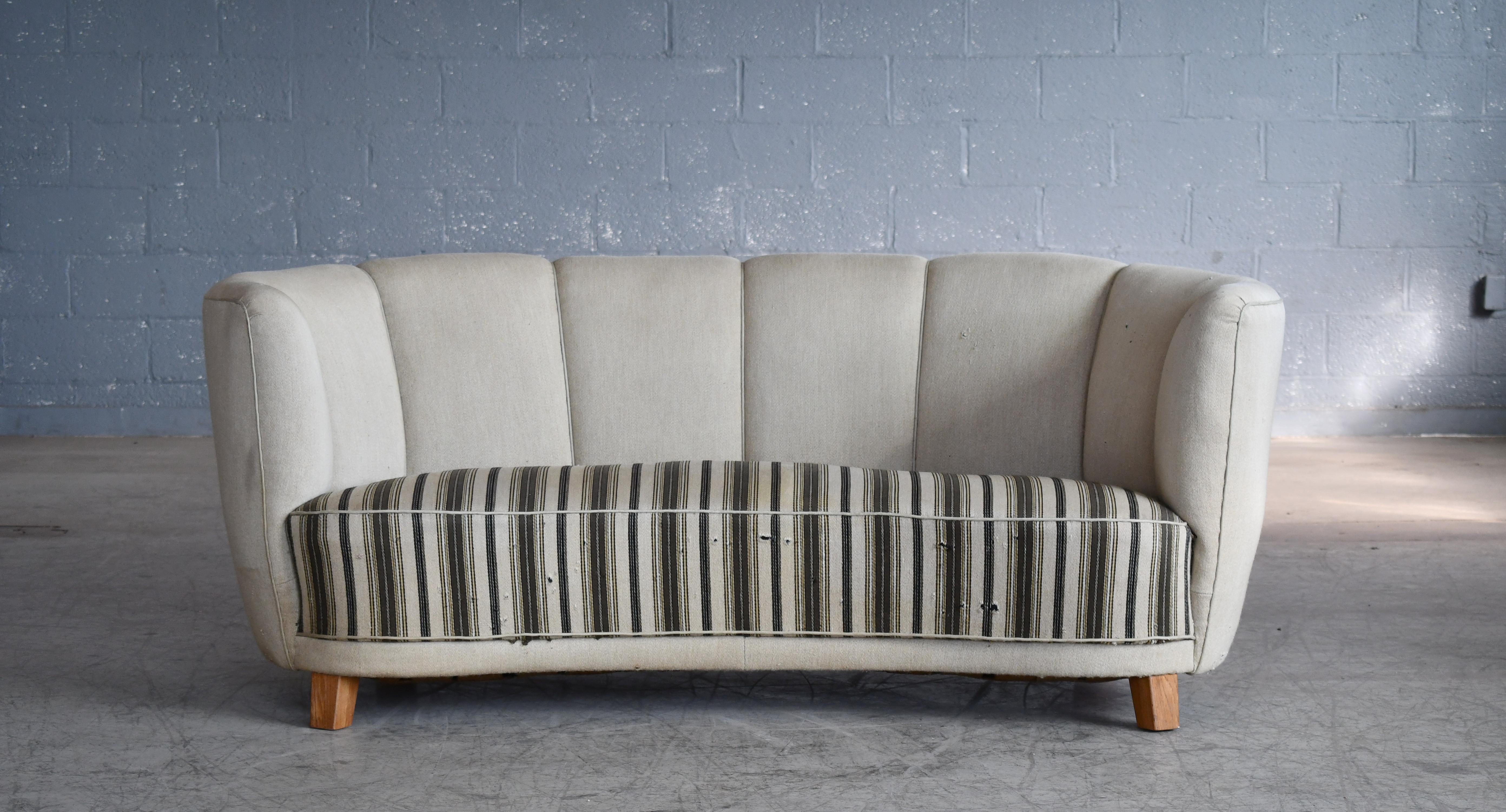 Beautiful and very elegant Danish 1940s curved two-seat sofa raised on a beech frame and legs. Solid construction with springs in the seat and the backrest for support and cushioning. The sofa was re-upholstered in recent years and the fabric is in