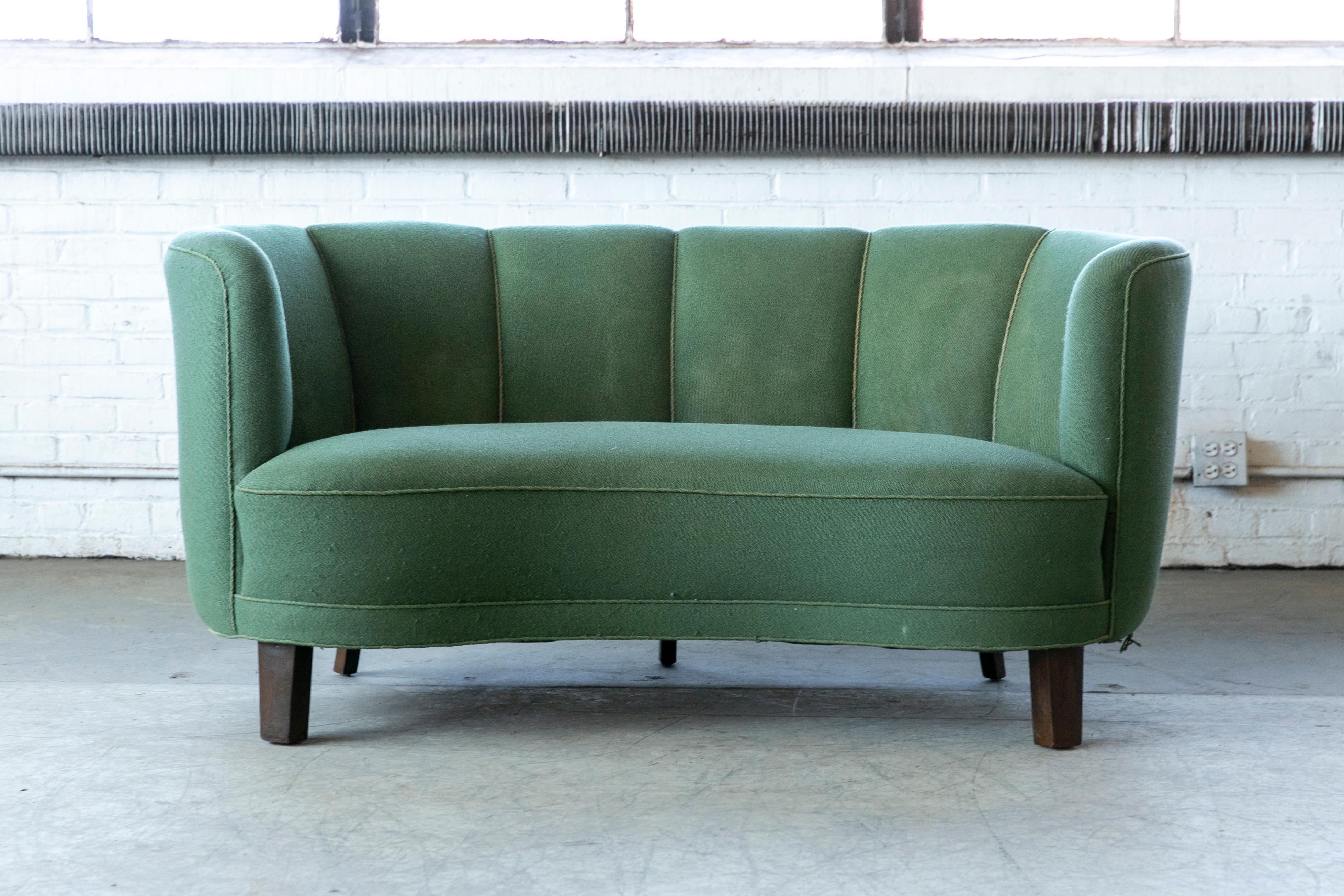 Beautiful and very elegant 1940s curved two-seat sofa or loveseat in green wool fabric. This sofa has slightly taller legs indicating a production date closer to 1950 when taller legs became more popular. The sofa has springs in the seat and the