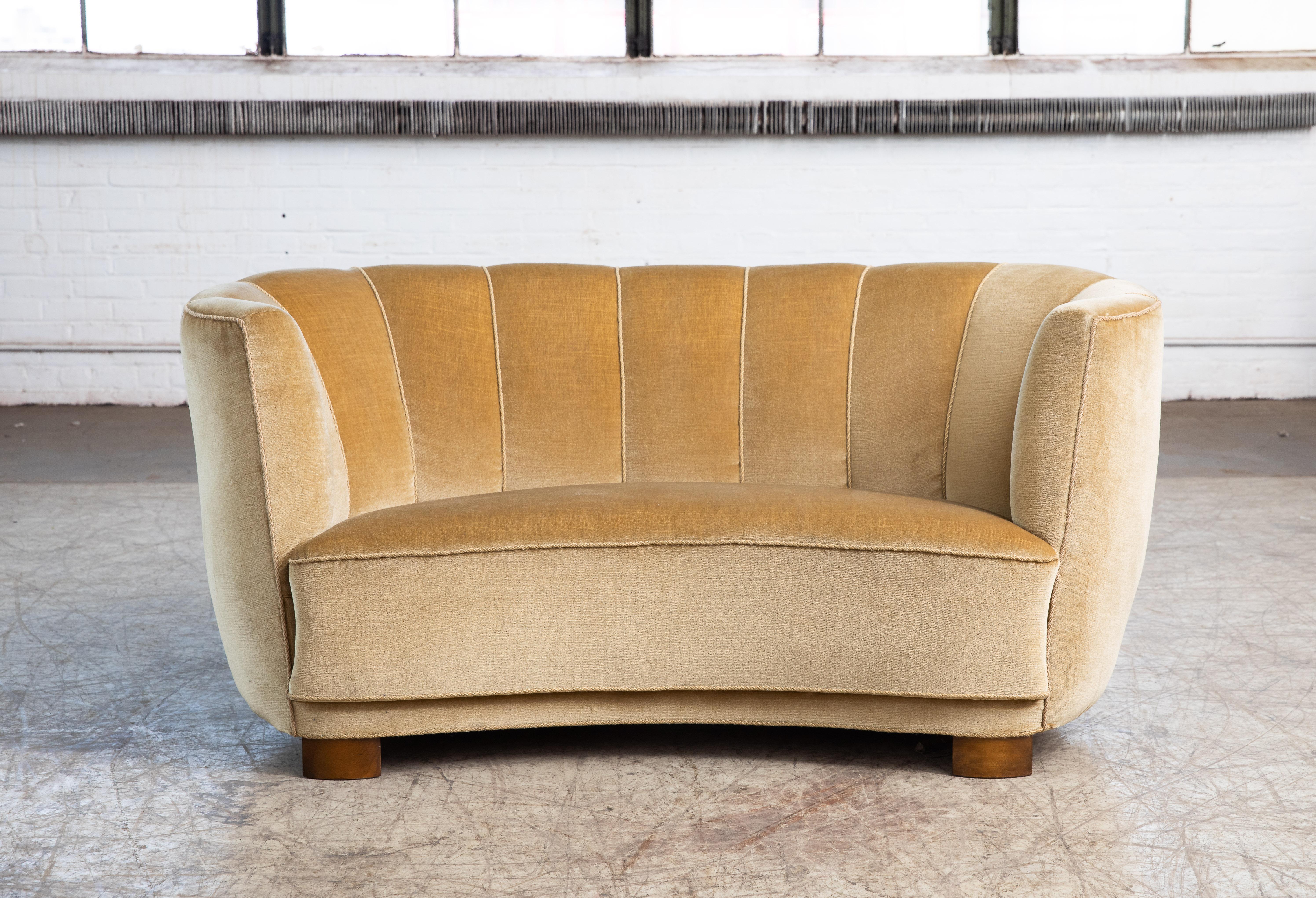 Viggo Boesen style banana shaped or curved Loveseat made in Denmark, circa 1940. This small sofa will make a strong statement in any room. Beautiful round voluptuous lines and with large block legs. Re-upholstered at a later pont in a yellow mohair