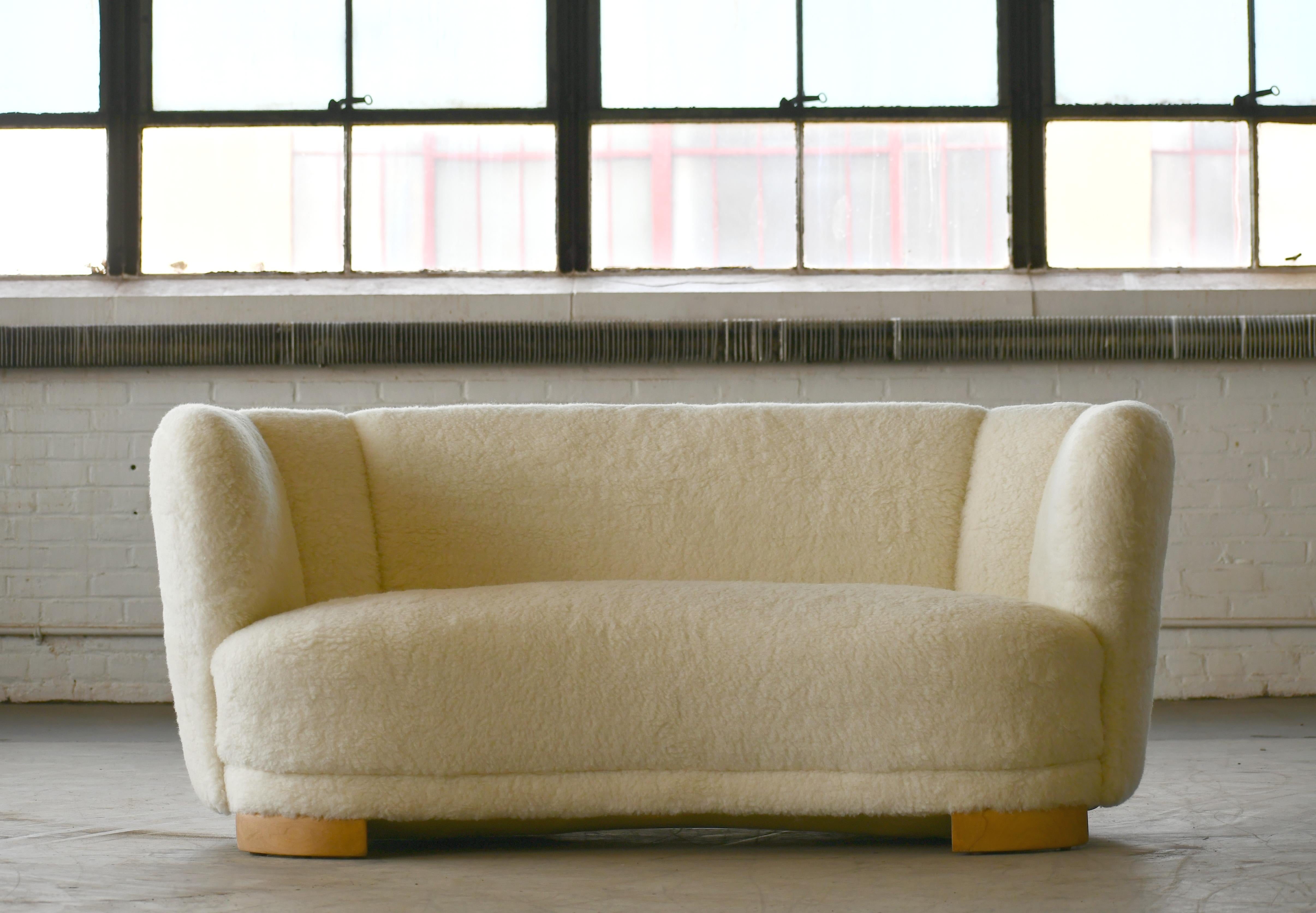 Viggo Boesen style banana shaped or curved sofa reupholstered in new lambswool made by Slagelse Møbelværk in the 1940s. This sofa will make strong statement in any room. Beautiful round voluptuous lines and with large block legs. Fully refurbished