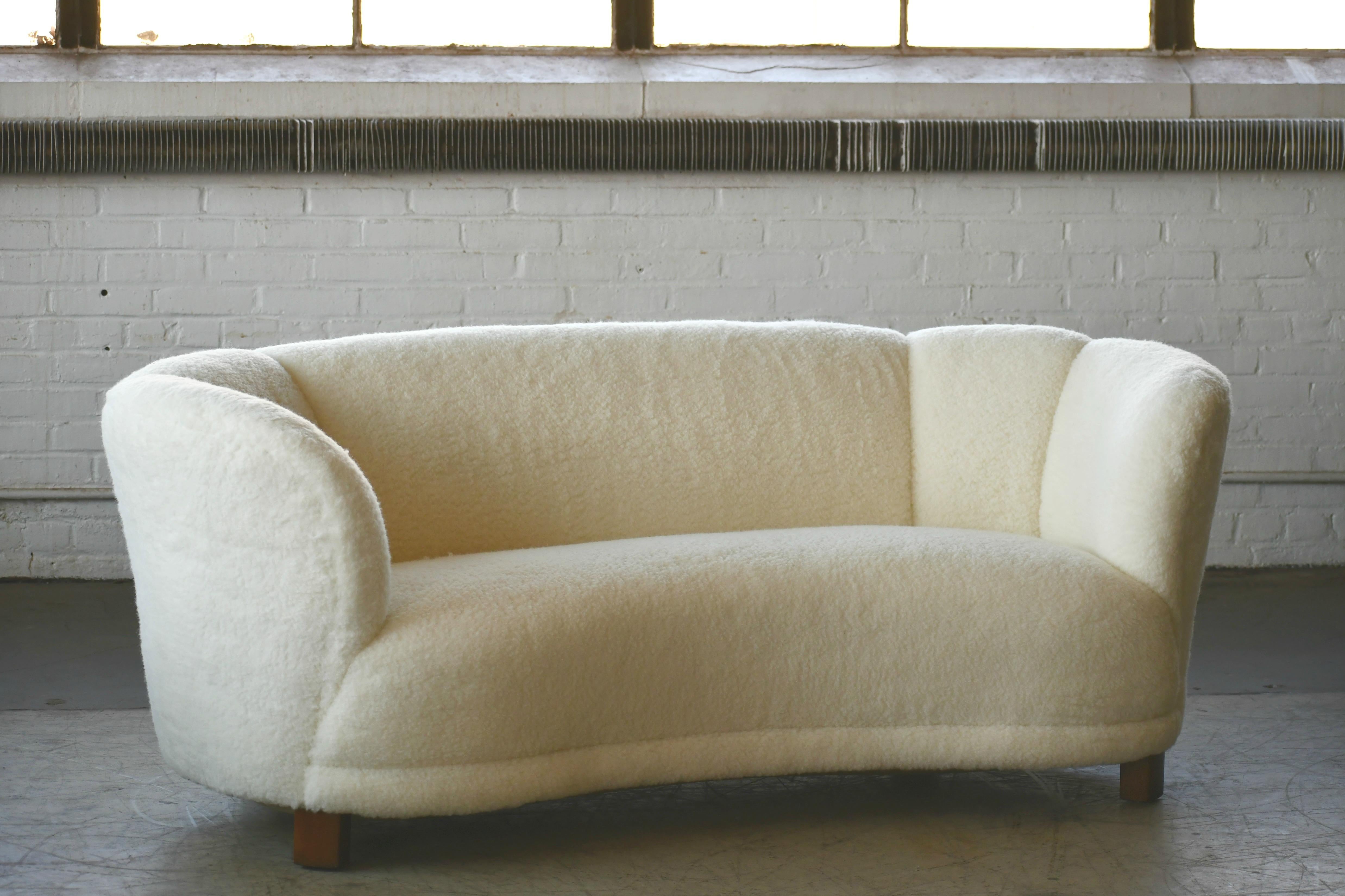 Viggo Boesen style banana shaped or curved sofa reupholstered in new lambswool made in Denmark in the 1940s. This sofa will make strong statement in any room. Beautiful round voluptuous lines and with large block legs. Fully refurbished and newly