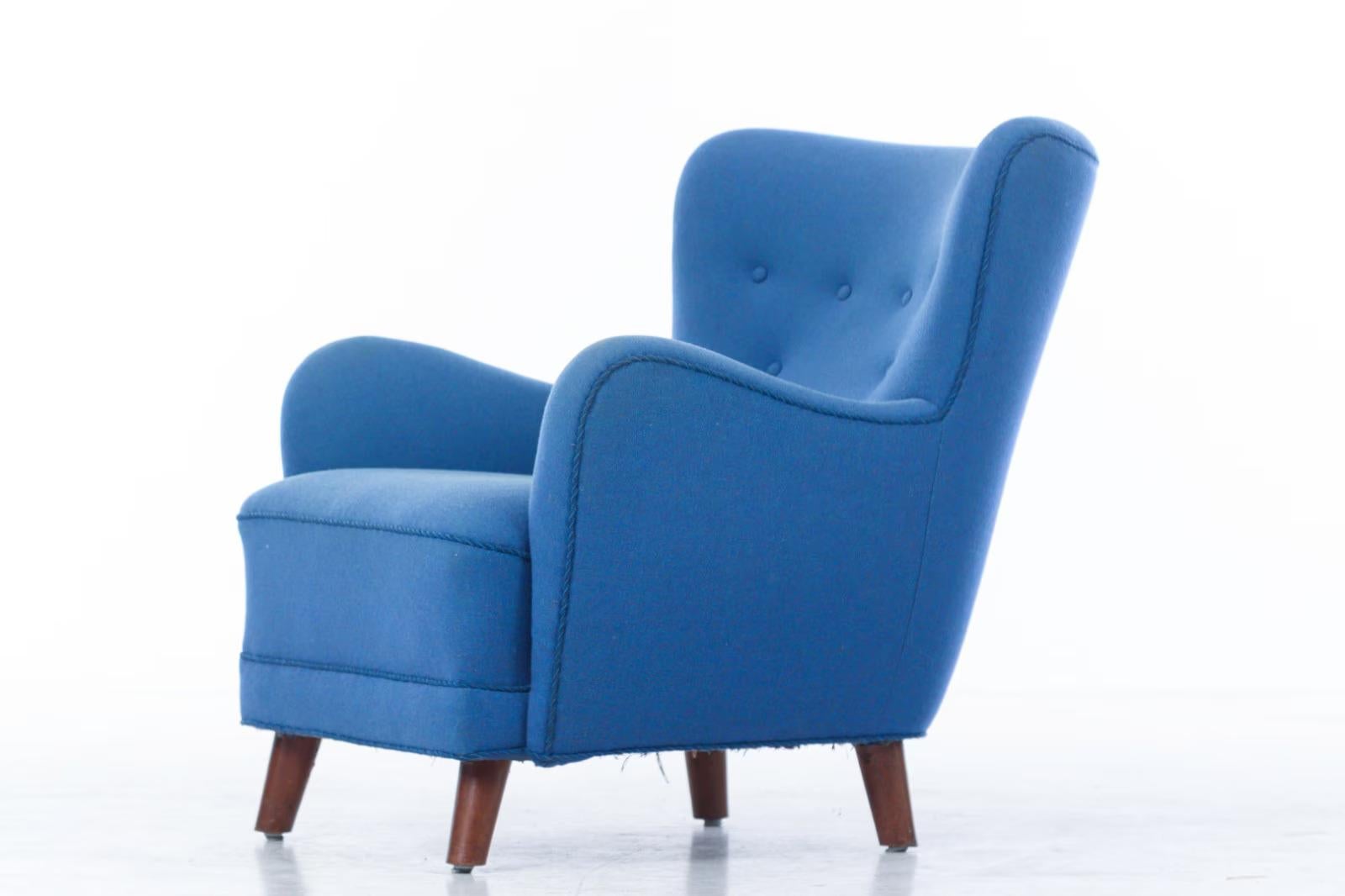 Curvy and eye-catching Danish club chair from the 1940s or early 1950. The rounded armrests are very much in the style of Flemming Lassen. Sturdy and sound construction with frame and legs made from beech. Coil springs in the seat. Later