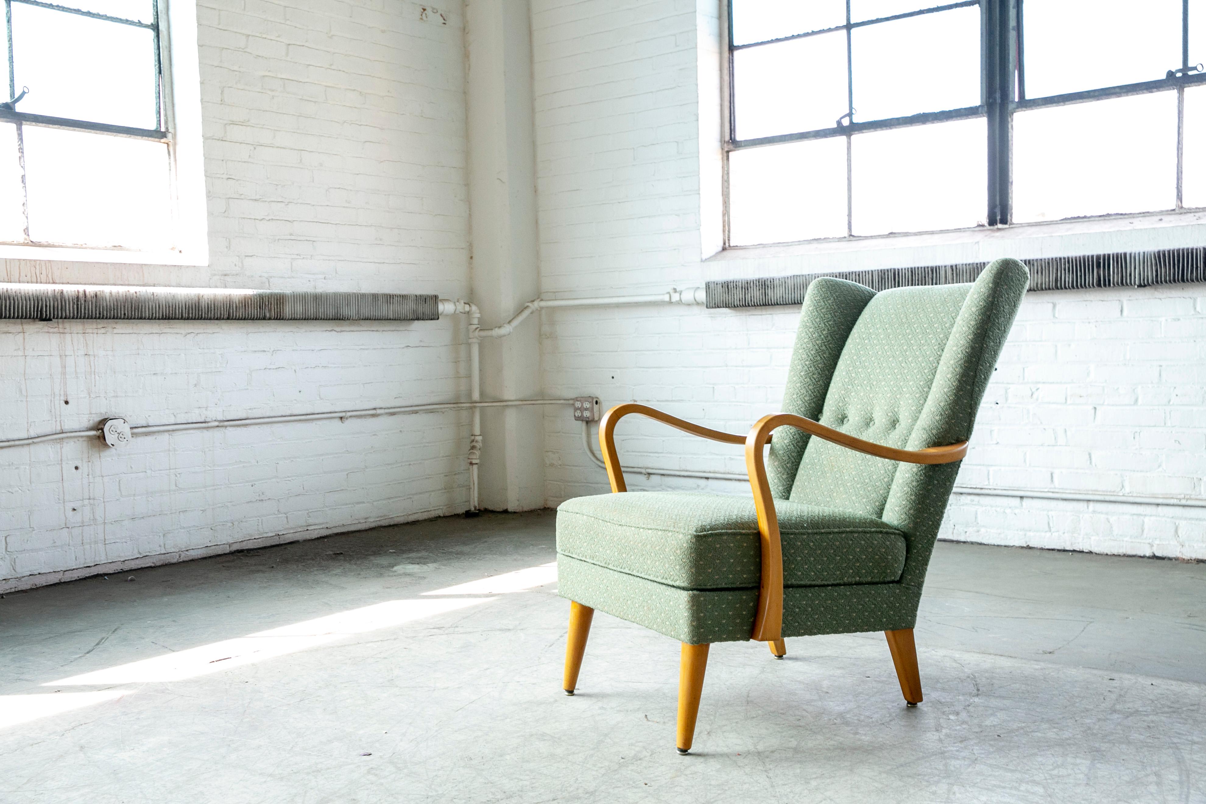 Very cool low swung Danish wingback lounge chair very similar to Fritz Hansen's and Alfred Christensen's design but unmarked and we are not sure of the maker nor the Designer. Great elegant angles and proportions with carved wooden armrests and legs