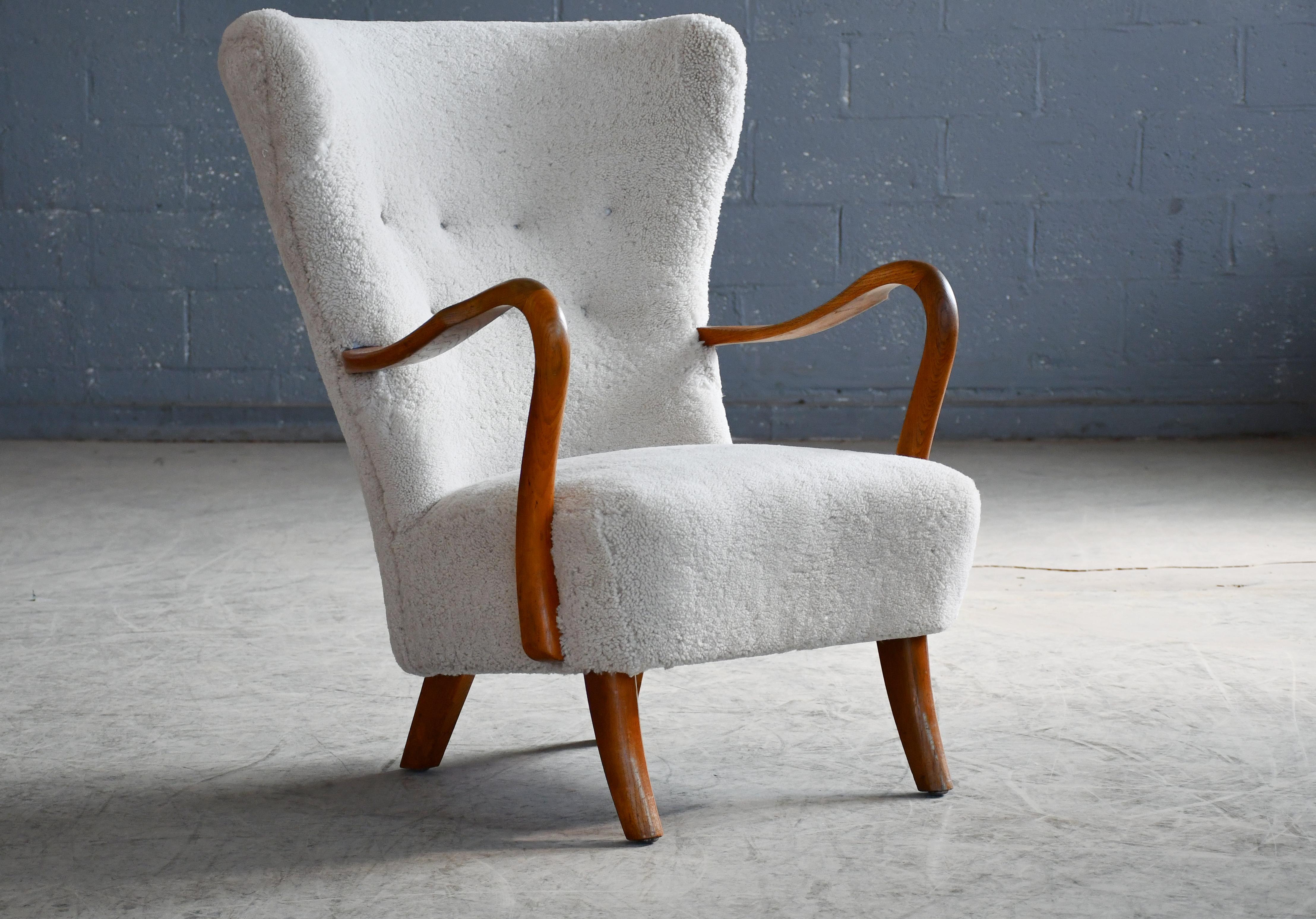 Classic elegant Danish high back armchair from the 1940s by Alfred Christensen for Slagelse Mobelvaerk with open armrests in beautifully carved stained beech wood. Nice slim elegant sculptural silhouette with saber shaped legs. Solid and sturdy