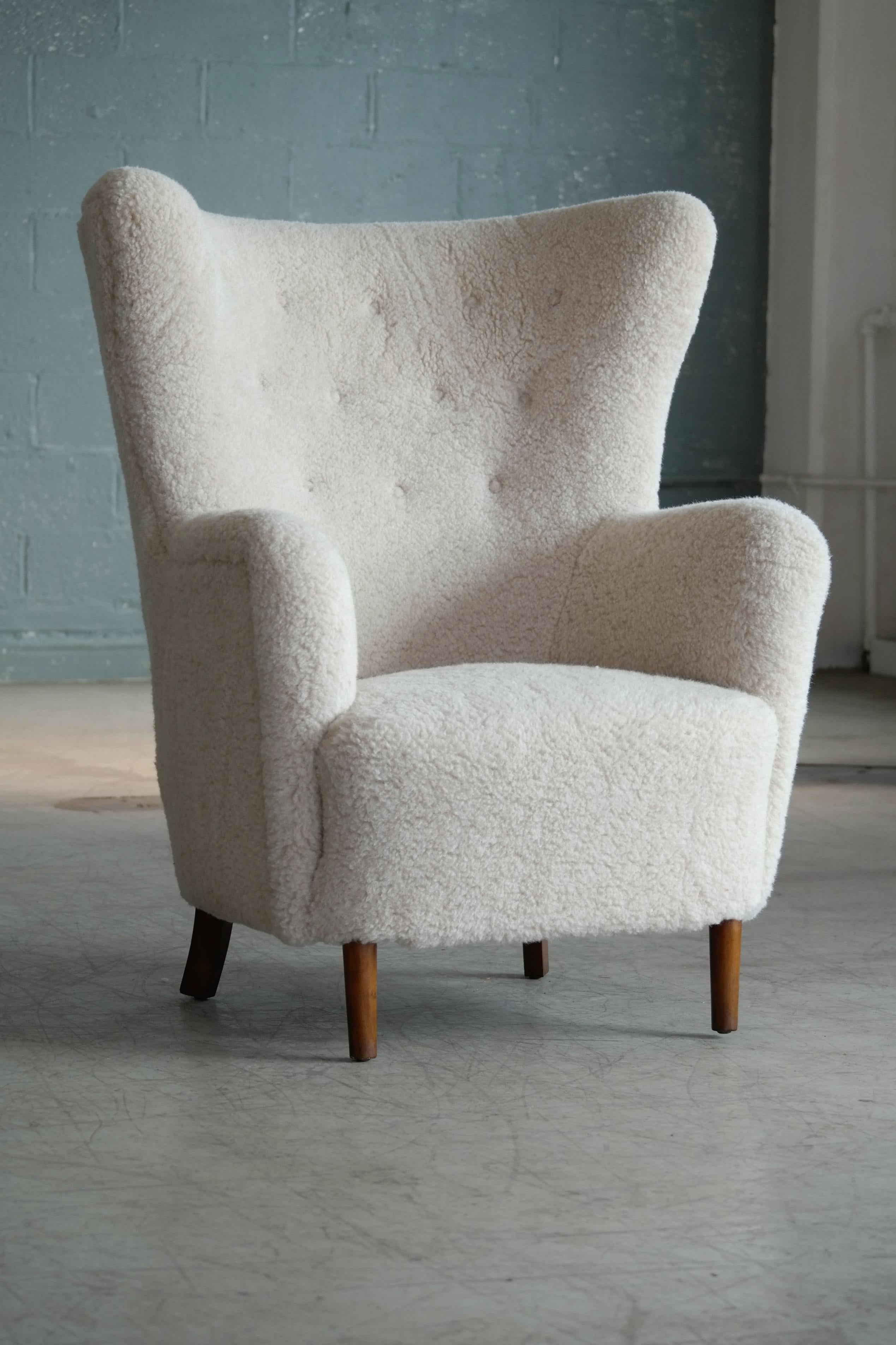 Beautiful and comfortable Flemming Lassen style high back lounge chair made in Denmark, circa 1940. Iconic and ultra-elegant look with the dainty cylindrical front legs and a beautiful silhouette. Perfect statement piece for any room. Spring loaded