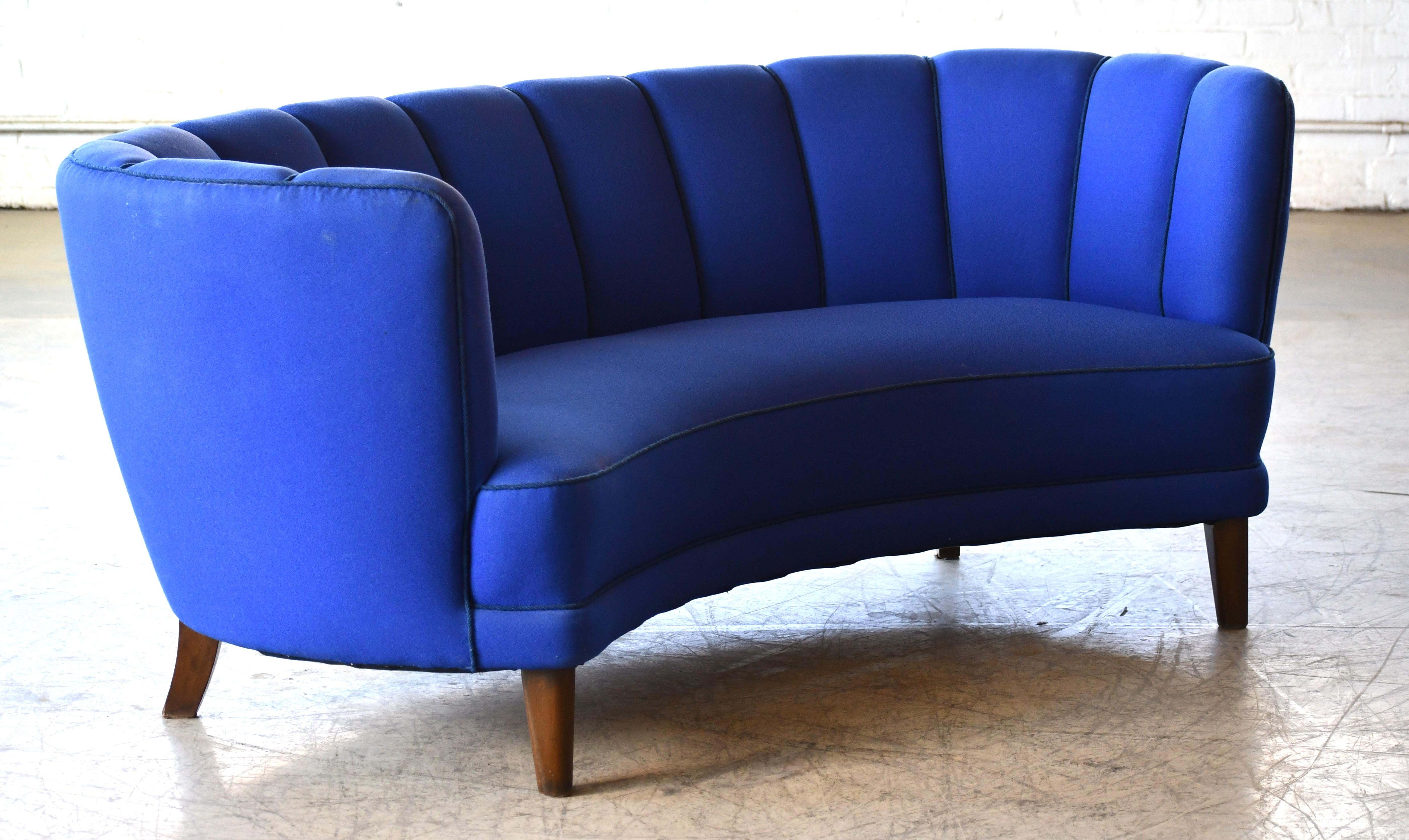 Magnifique et très élégant canapé trois places incurvé à dossier cannelé de grande taille des années 1940. Le canapé est équipé de ressorts dans l'assise et le dossier et le cadre en bois de hêtre est solide et robuste. Le tissu ajouté